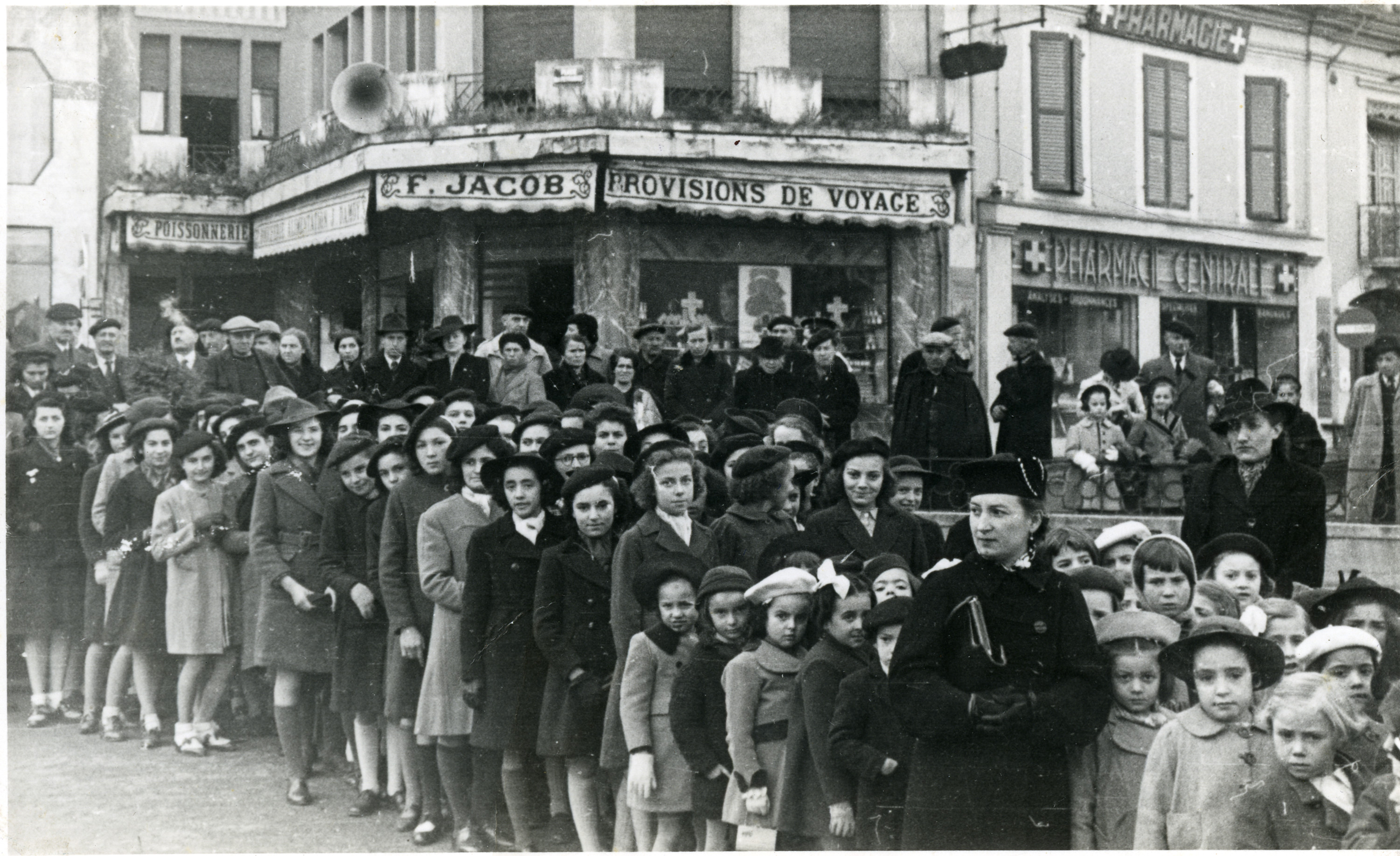 Ora standing in line waiting to greet Marshal Petain in Lourdes.

Ora is standing in the front row, the third child behind the woman dressed in black, holding a purse.