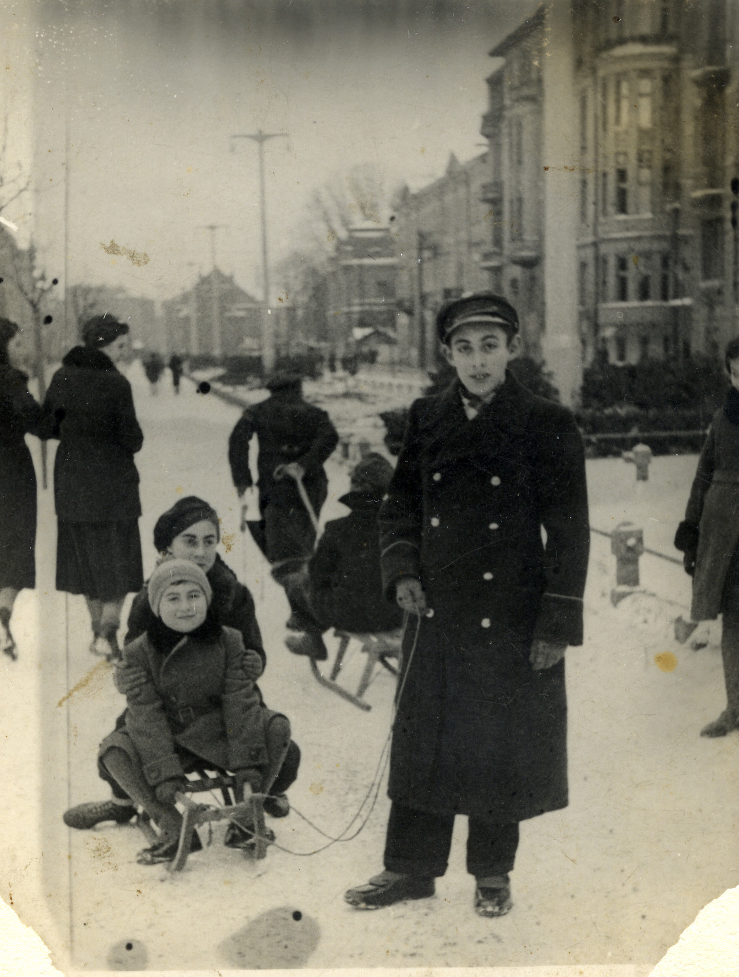 Jewish siblings go sledding in the streets of Kalisz, Poland.

Pictured in front are Ester and Michael Gluba (seated on the sled), with Szamszon Gluba (standing, pulling the sled).