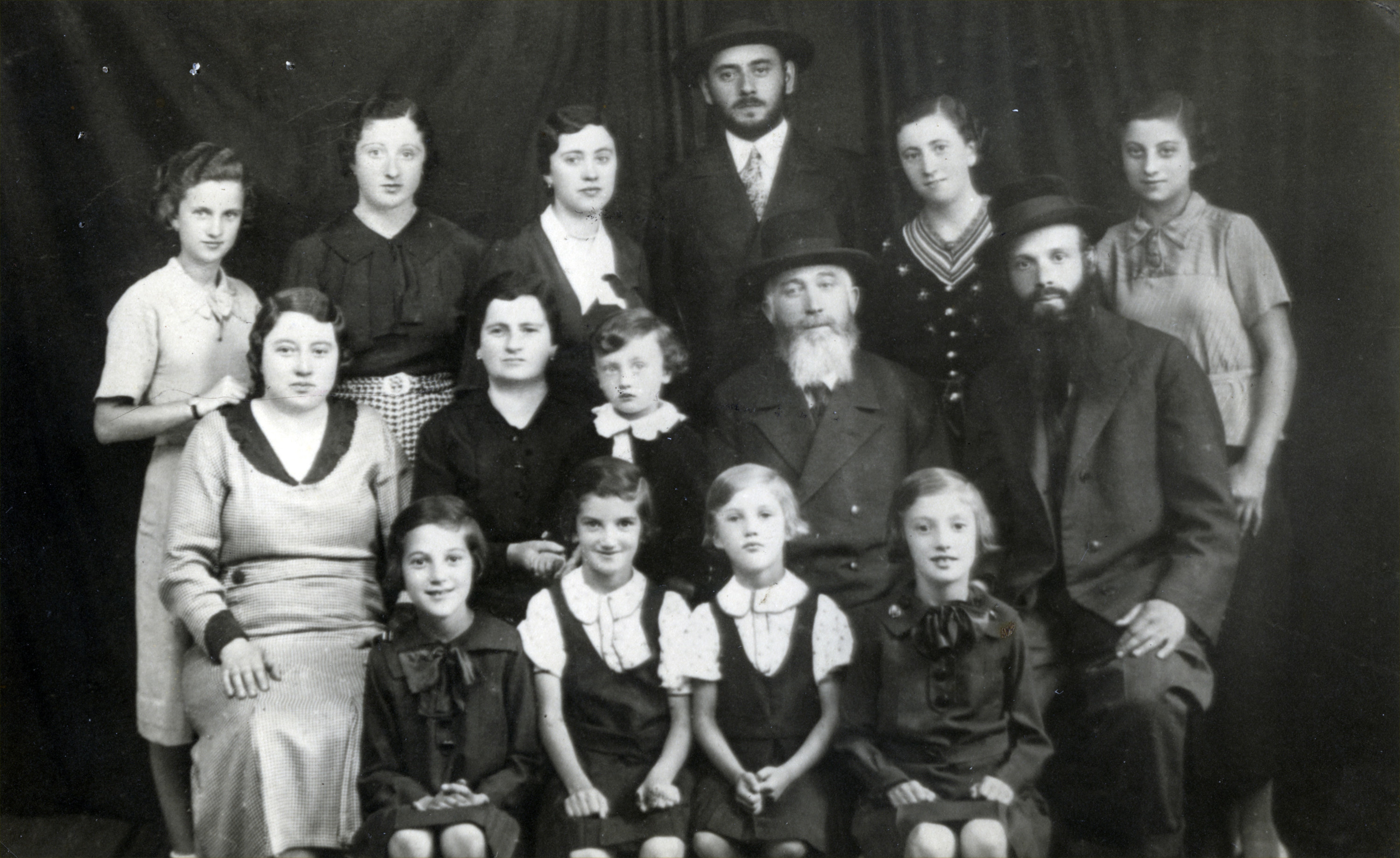 Group photograph of  the Scheiner family in Khust, Czechoslovakia.

Pictured are Lazar and Sharona Scheiner (middle row, fourth and second from the left). Their children are (back row, left to right) Bella, Manci, Berta , Yenu-Jacob, Flora, and Sidi (pictured in the middle row, far left).  Sidi's husband Yeheskel is pictued in the middle row, on the far right.  Berta's son, Liebiku is seated between Lazar and Sharona.  Seated in the front row are Sidi and Yeheskel's daughters Etu, Tuti, Malka, and Dvora.