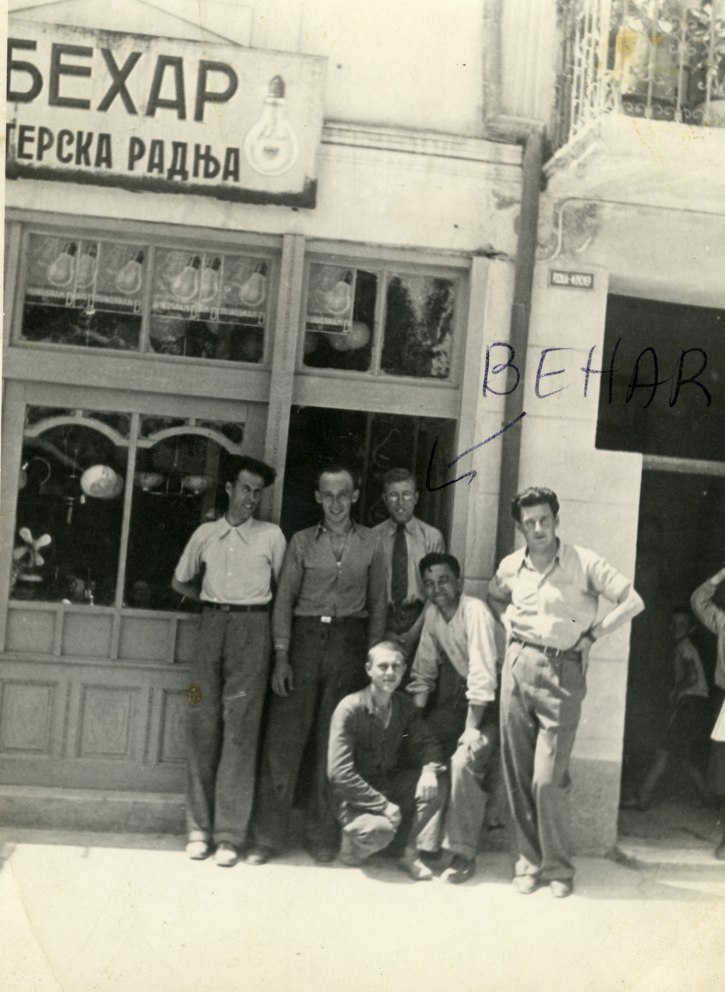 Owners of an electical store pose at its entrance, with friends.

Among those pictured is Aharon Behar (standing in back, wearing glasses) and his friend and business partner Aleksander Todorov (far right).