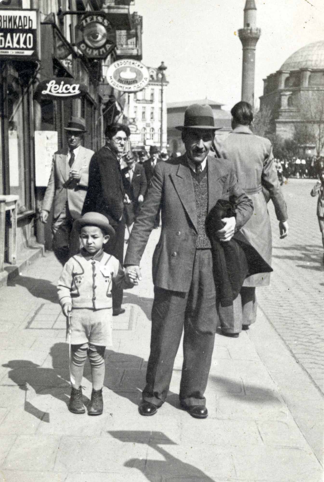 Leon Buka and his son Avraham pose in the street in Sofia, Bulgaria.  

Ruins of the Ancient Roman Ampitheater can be seen in the background.