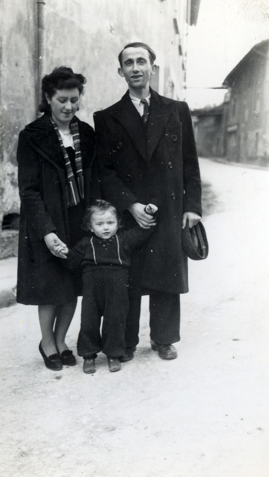 A French Jewish family stands for photograph on the street of Moirans, France.

Pictured are Laja and George Tannenbaum, with their son Lazare.