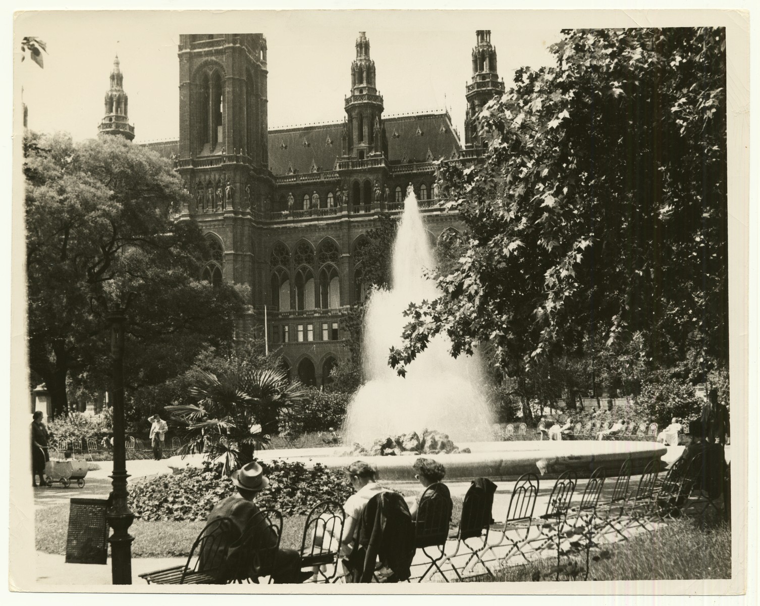 Photograph of the restored Rathhauspark (City Hall Park) in Vienna, Austria. City Hall appears in the background.

The handwritten caption on the back of the photograph reads: "Restaurated [sic] "Rauthauspark" in Vienna.  City Hall in background."