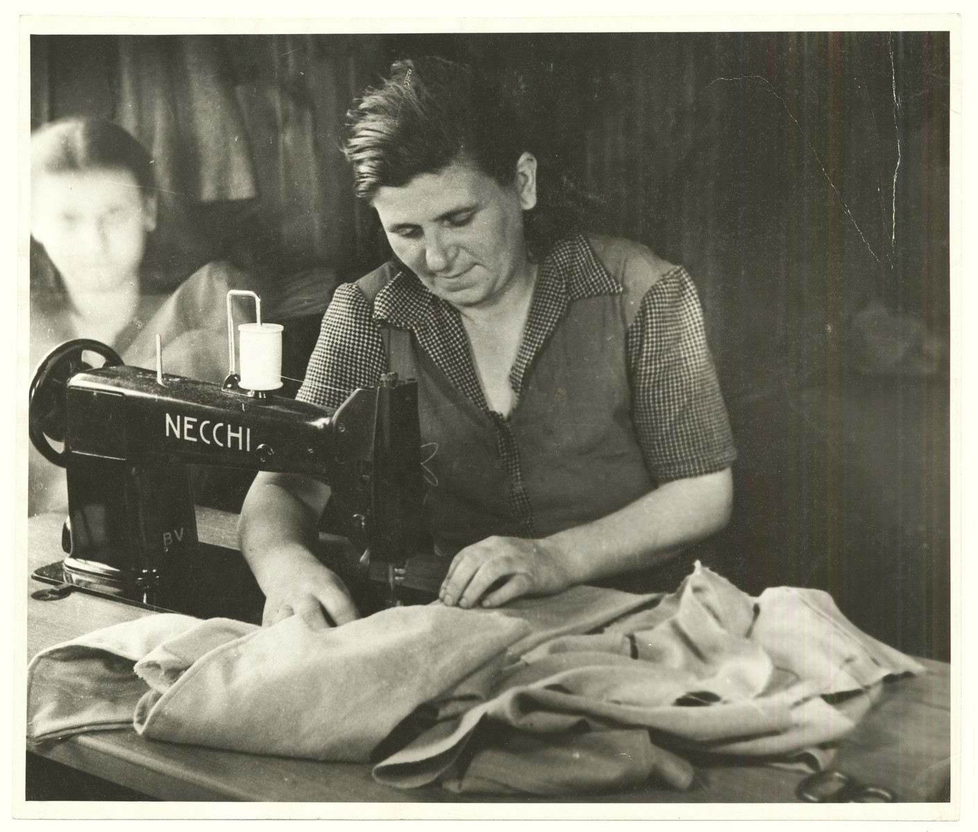 A woman works in a sewing factory in a displaced persons camp, probably in Vienna.