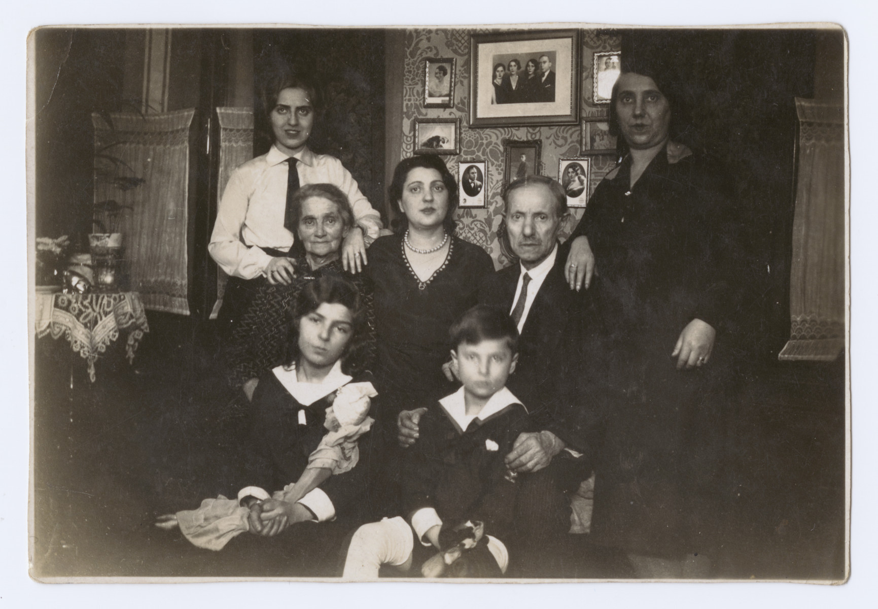 The extended Schwarz family poses for a group portrait in their home.  

Marta Koranyi is at the bottom left; her brother Erwin is at the bottom right.  Also pictured are her parents, Sigmond and Sara (nee Schwarz) Koranyi , and grandparents.  Her maternal aunt is at the top right.