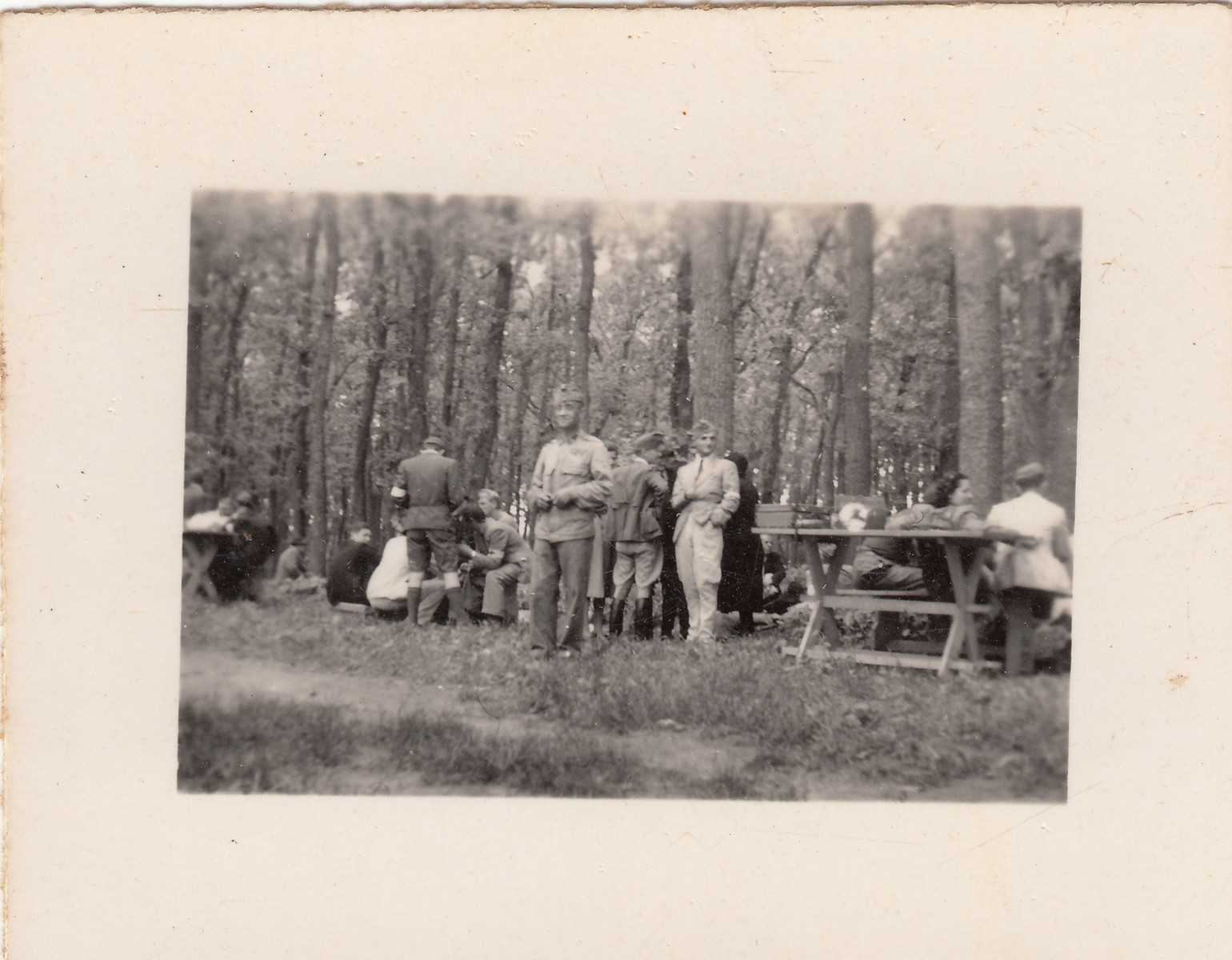 Members of a Hungarin labor battalion stop for lunch at a picnic table.  They are joined by a group of visitors.