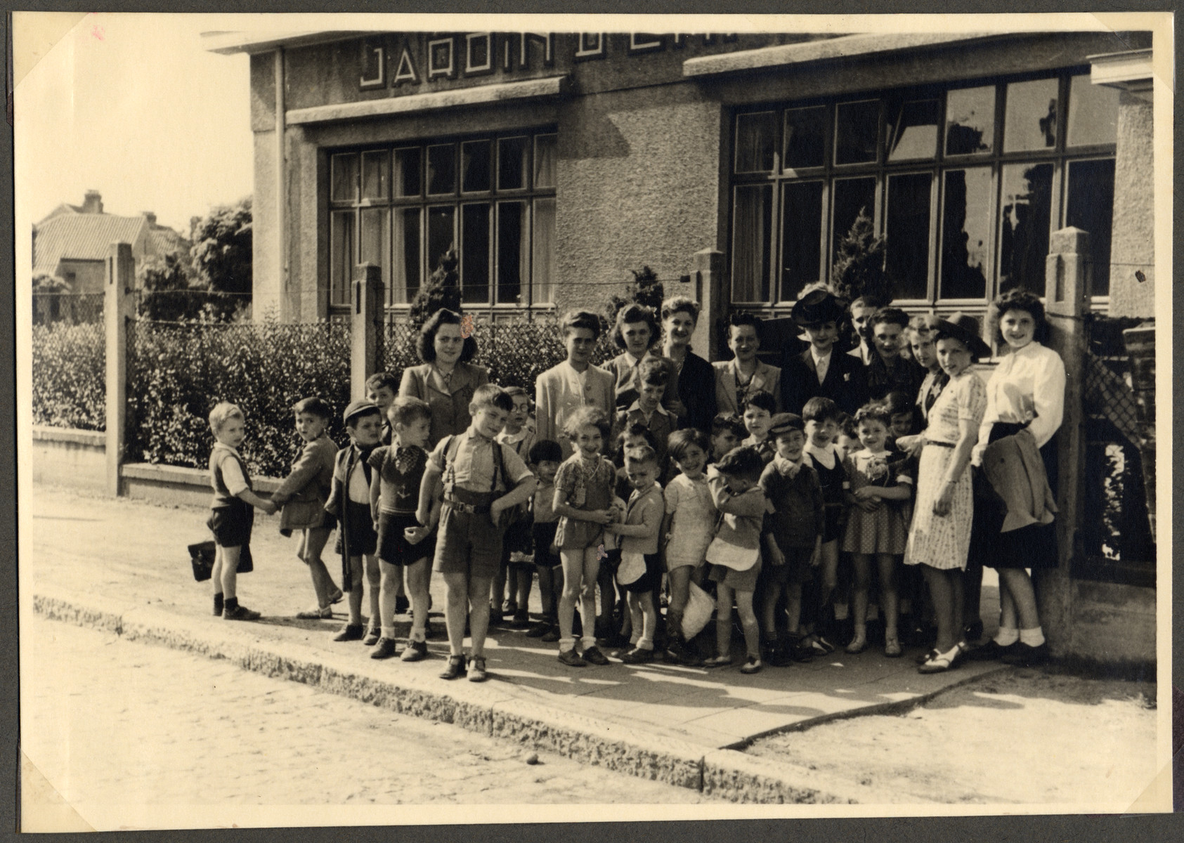 Group portrait of children and teachers in the Nos Petits children's home.

Jewish staff members are wearing a Star of David.