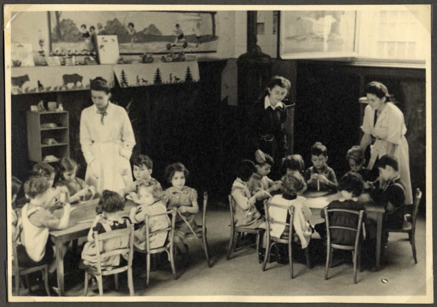 Children sit at tables to do an art project in a classroom in the Nos Petits Jewish kindergarten.

The teacher in the center is wearing a Star of David.