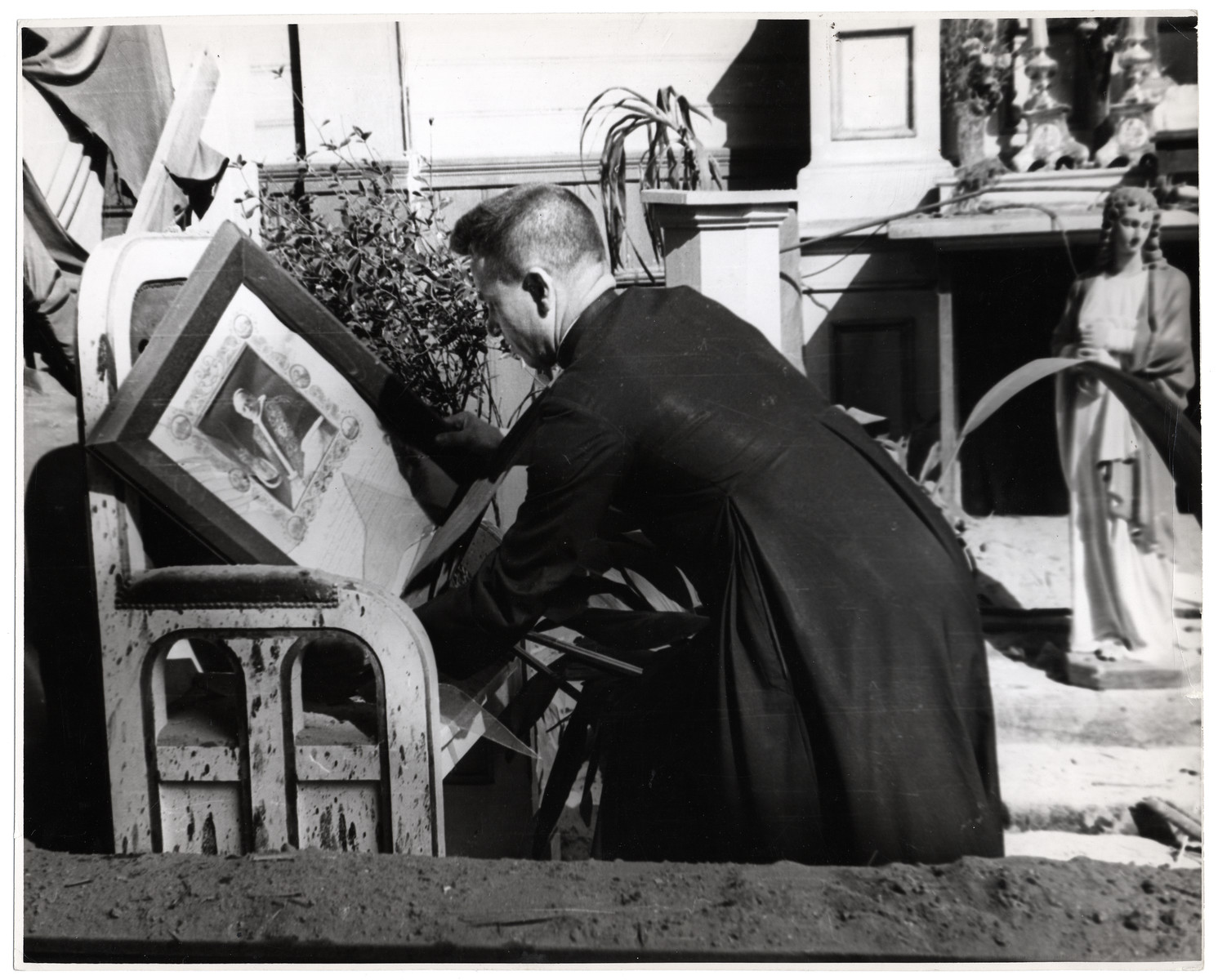 A Polish Catholic Priest removes religious iconography from a destoyed church - including a statue of the Virgin Mary and a portrait of Pope Pius XII.