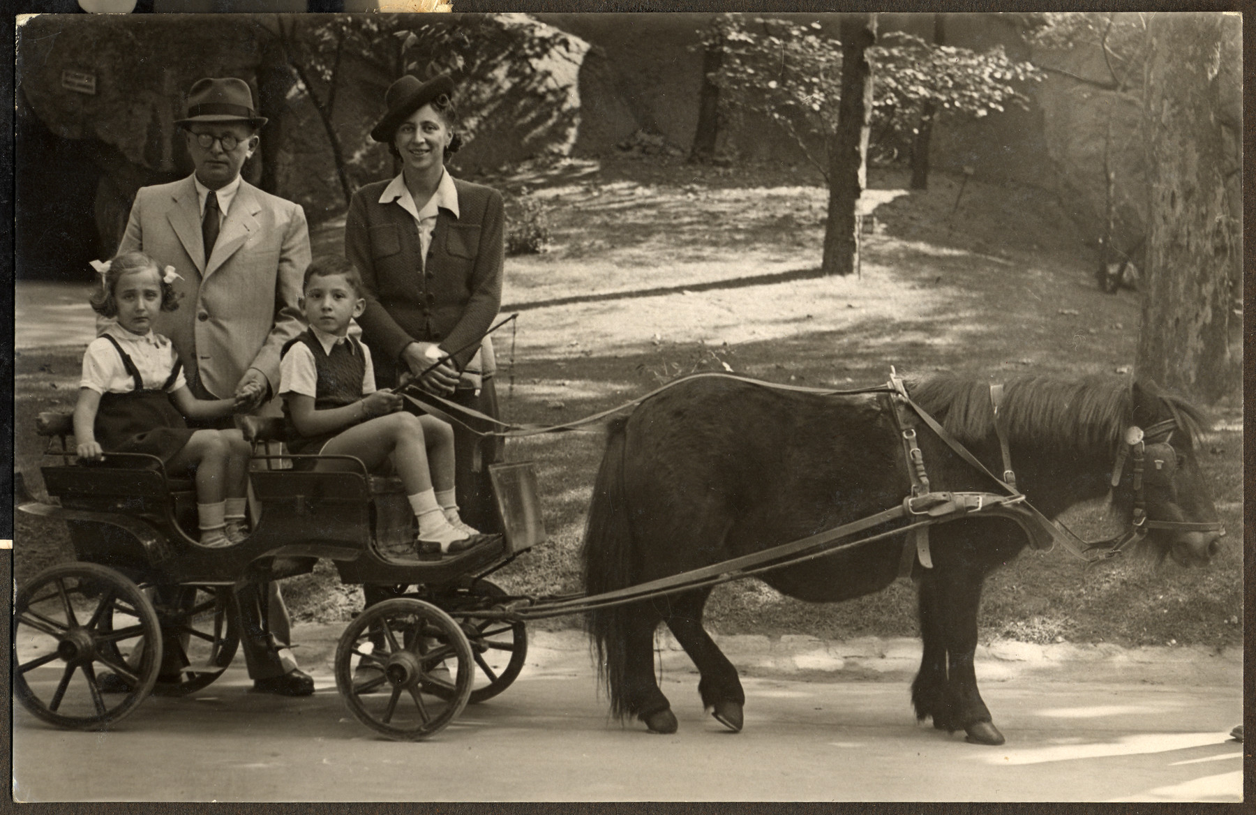 Two children go on an excursion on a pony cart in the zoo.

Pictured in the cart are Manny Mandel and his cousin Yudit Krishaber.  Standing behind them are Erno Krishaber and Ella Mandel.

Shortly afterwards, Yudit perished in Auschwitz and her father Erno Krishaber perished in a Hungarian labor camp.