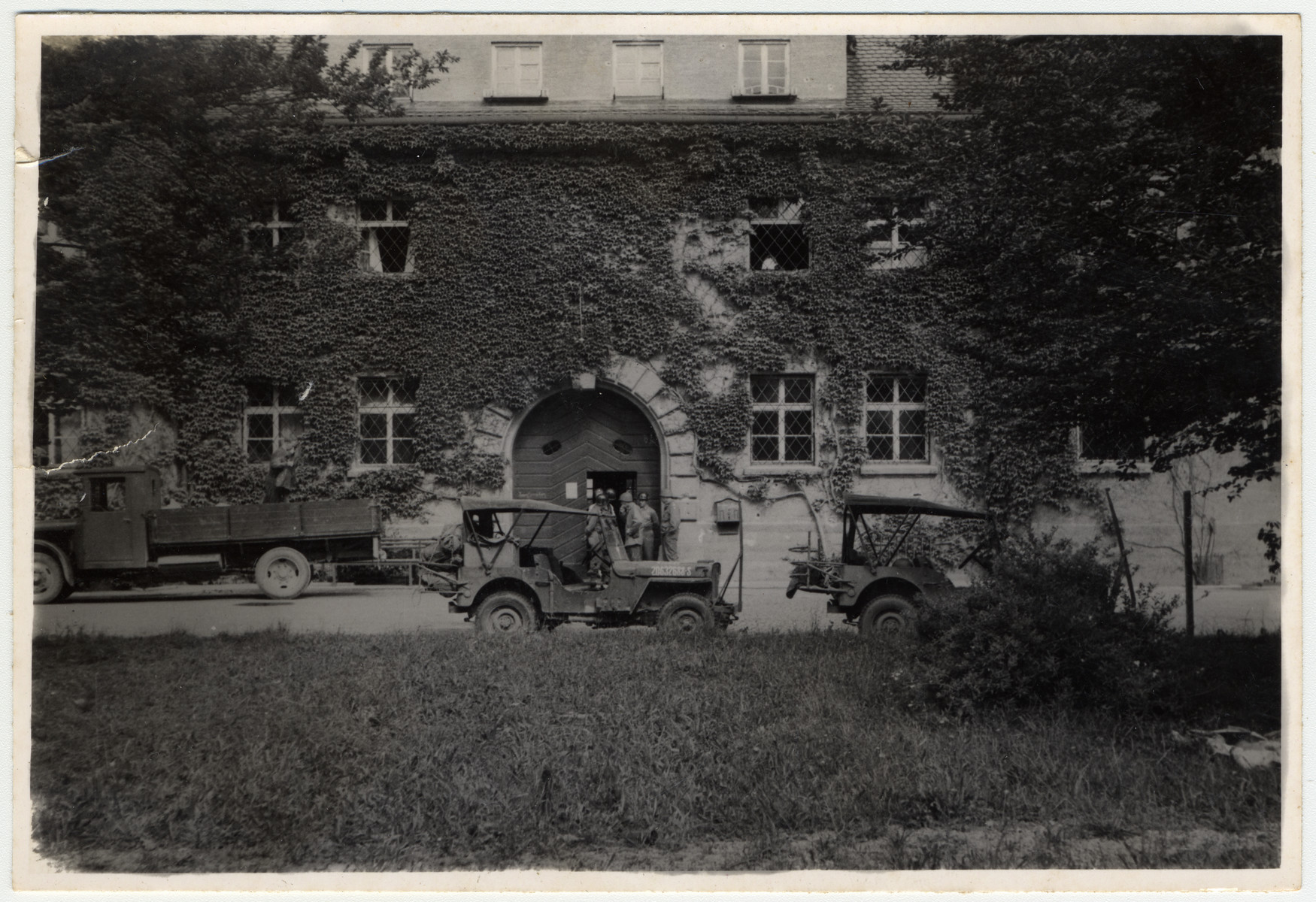 Exterior view of the front of the Landsberg prison with several military vehicles parked outside.