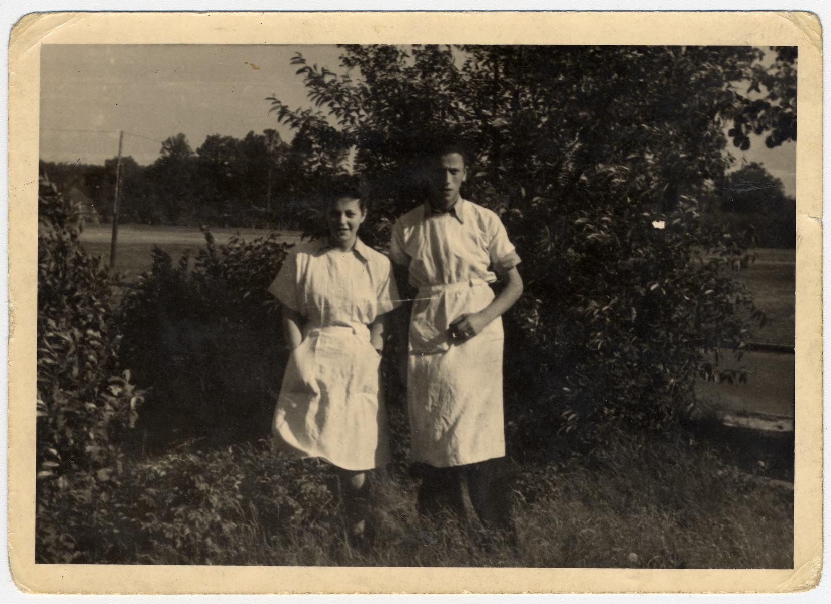 Two dental technician students stand in a garden in the Bergen-Belsen displaced persons camp.

Erno Pollak is on the right.