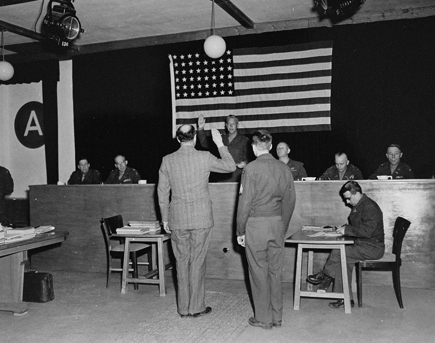 A witness is sworn in at the trial of 61 former camp personnel and prisoners from Mauthausen.  Swearing him in is Major General Fay Brink Prickett, the President of the Military Tribunal.