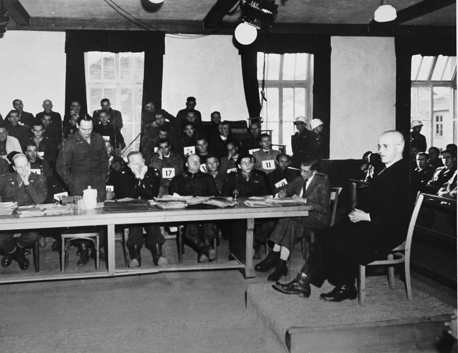 Father Johann Maria Lenz, a former inmate of Dachau, testifies at the trial of former camp personnel and prisoners from Dachau.  

Lenz was commissioned by the Vatican to write a book about the camp.