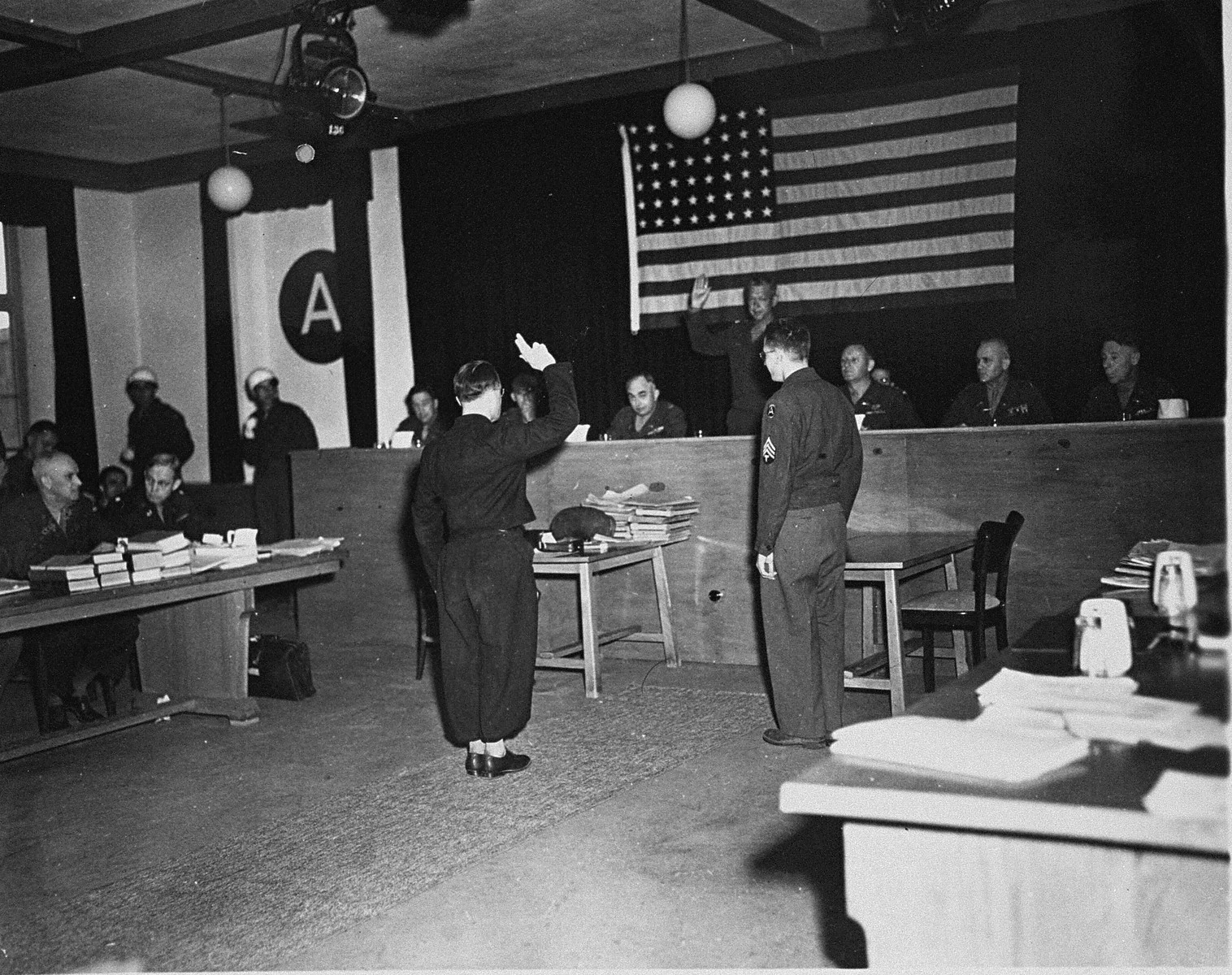 A witness is sworn in at the trial of 61 former camp personnel and prisoners from Mauthausen.  Swearing him in is Major General Fay Brink Prickett, the President of the Military Tribunal.