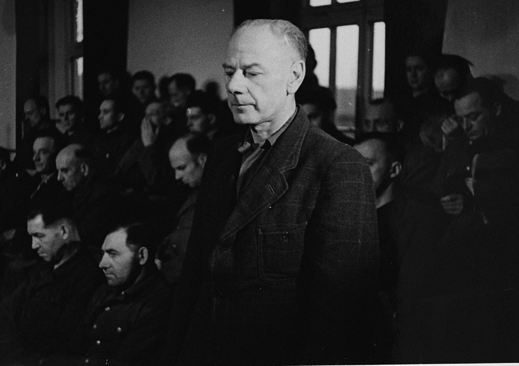 Dr. Eduard Krebsbach, a defendant at the trial of 61 former camp personnel and prisoners from Mauthausen, stands in his place in the defendants' dock.