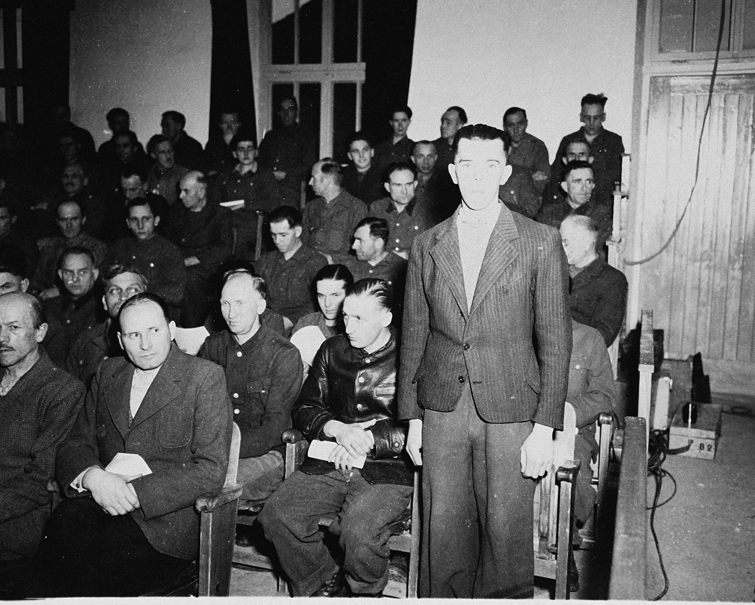 Former SS-Unterscharfuehrer Andreas Trumm, a defendant at the trial of 61 former camp personnel and prisoners from Mauthausen, stands in his place in the defendants' dock.  

Trumm was convicted and sentenced to death on May 13, 1946.