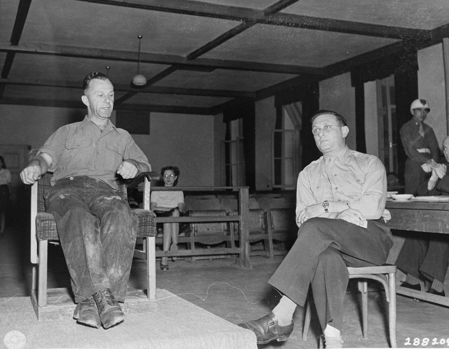 Hermann Grossmann, a former SS lieutenant, testifies in his own defense at the trial of 31 former camp personnel and prisoners from Buchenwald.  On the right is the interpreter, Rudolph Nathanson.