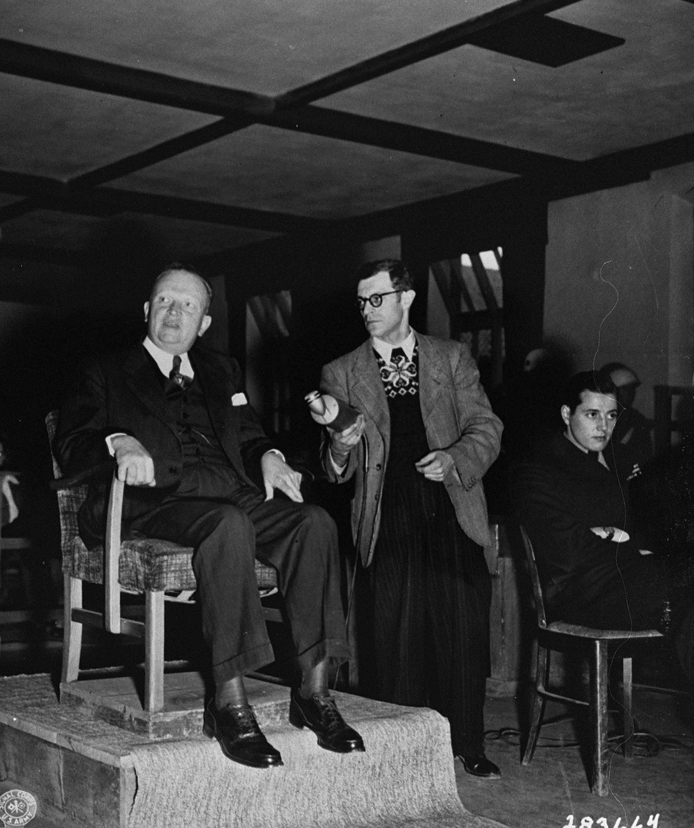 Karl Berthold testifies for the prosecution at the trial of former camp personnel and prisoners from Buchenwald.  To his left is Werner Klein, a radio reporter, and Fred Stecker, an interpreter.