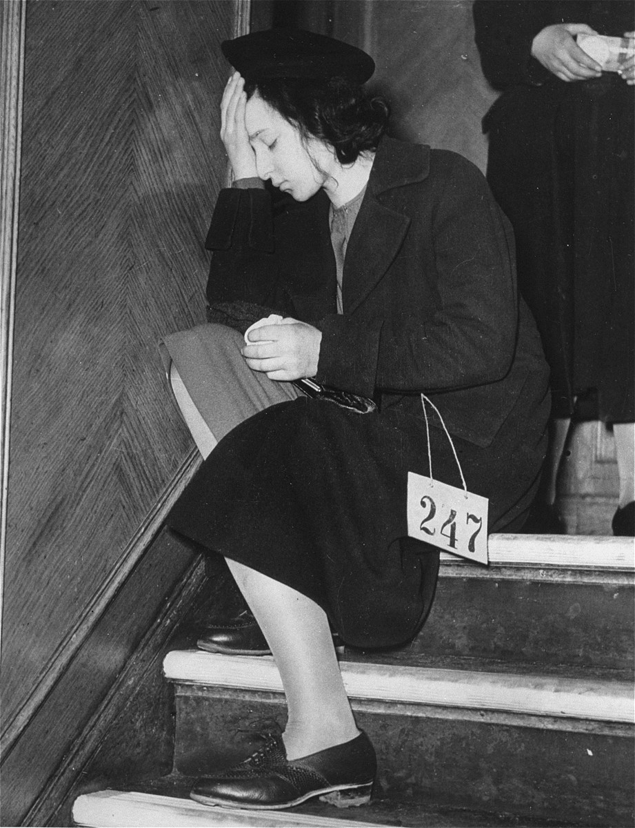 A Jewish youth, wearing a numbered tag, sits on a staircase with her head in her hands after her arrival in England with the second Kindertransport.
