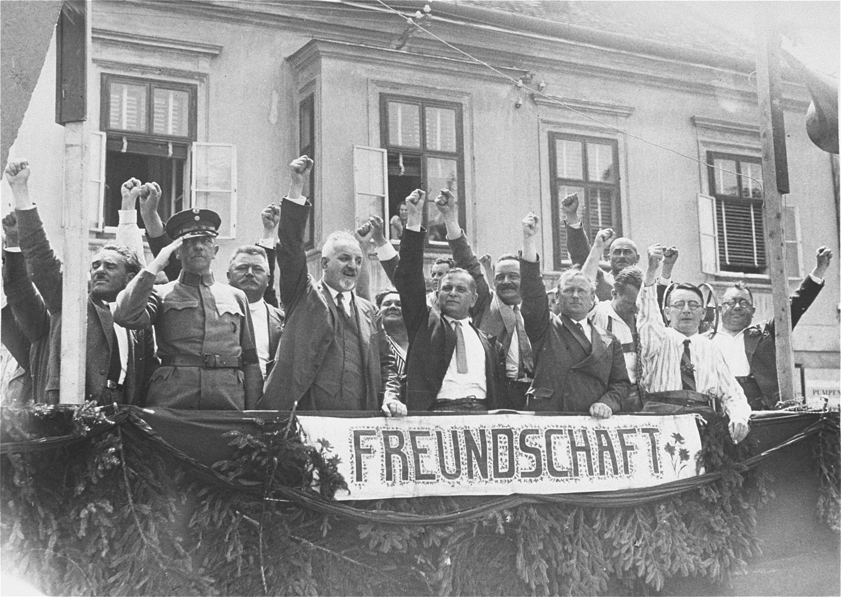 The leader of Austria's Social Democrats salutes the Republican "Schutzbund" during its demonstration against the Nazi storming of the Social-Democratic party house the previous week. 

Pictured from left to right, are Major Eifler, Military Commander of the Republican "Schutzbund"; Speiser, Town Councillor; Otto Bauer, National Deputy; Dr. Deutsch, leader of the Social Democratic Party; and Till, Commander of the "Schutzbund".