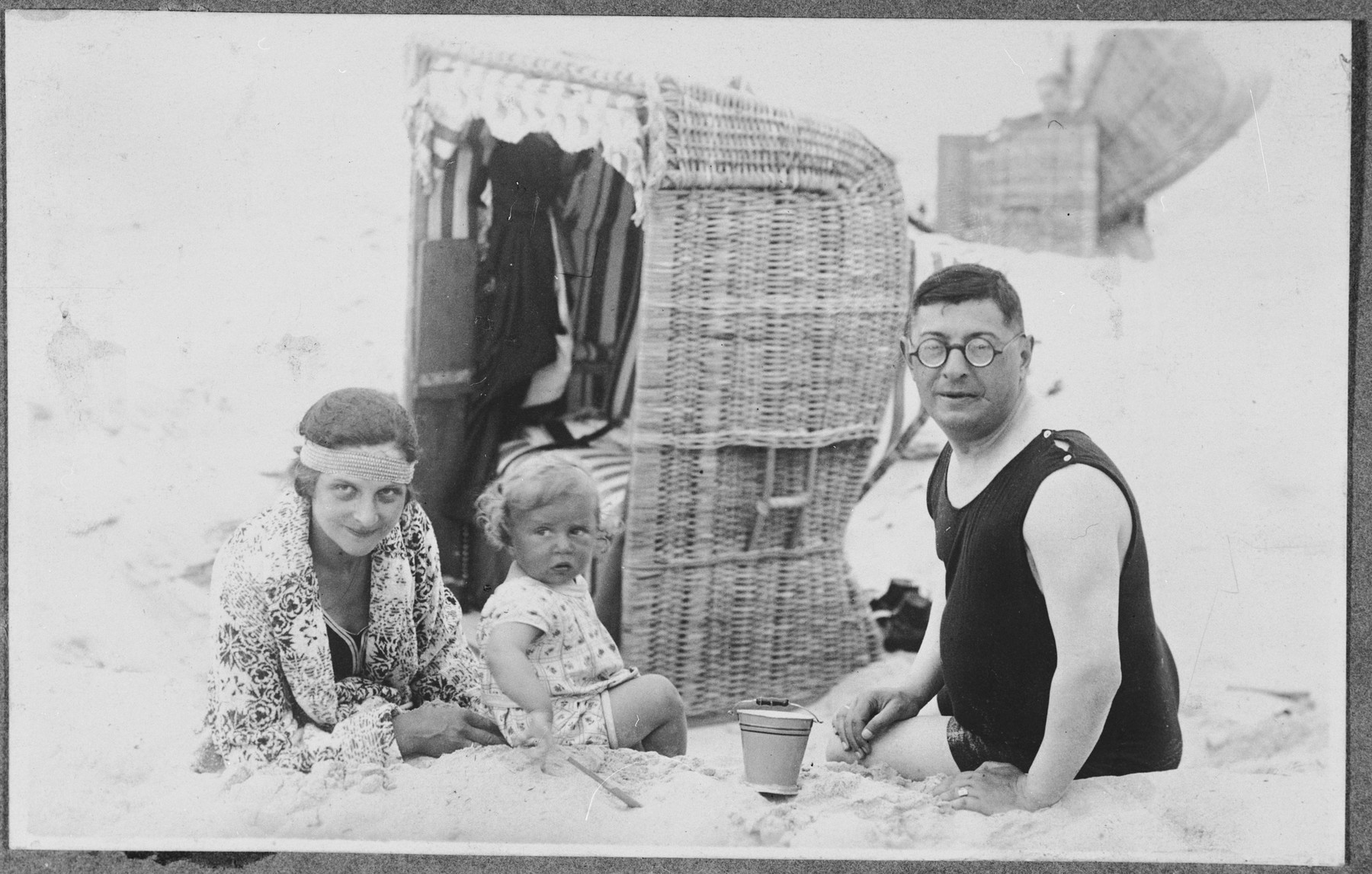 The Glueckstein family relaxes on a beach in front of a cabana.

Pictured from left to right are Hedwig, Fritz and Georg Glueckstein.