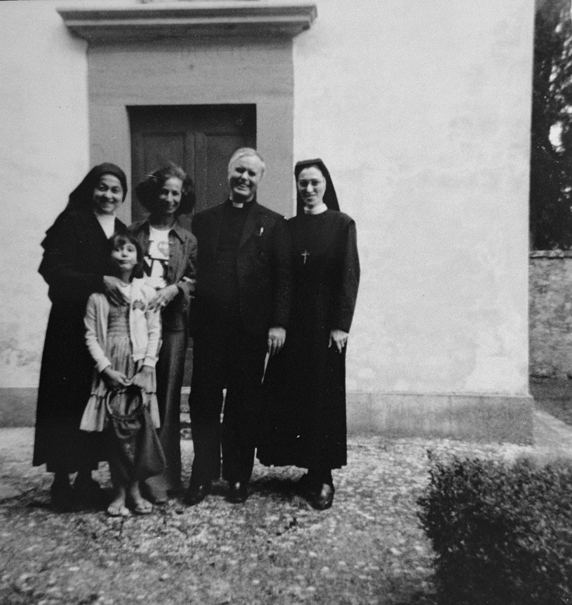 Italian rescuer Monsignor Beniamino Schivo poses with Ursula Korn Selig, a Jewish woman he had protected as a child during the German occupation of Italy.  

The group is standing in front of the oven at the villa of the Salesian nuns where Ursula and her family hid for two months in 1943.