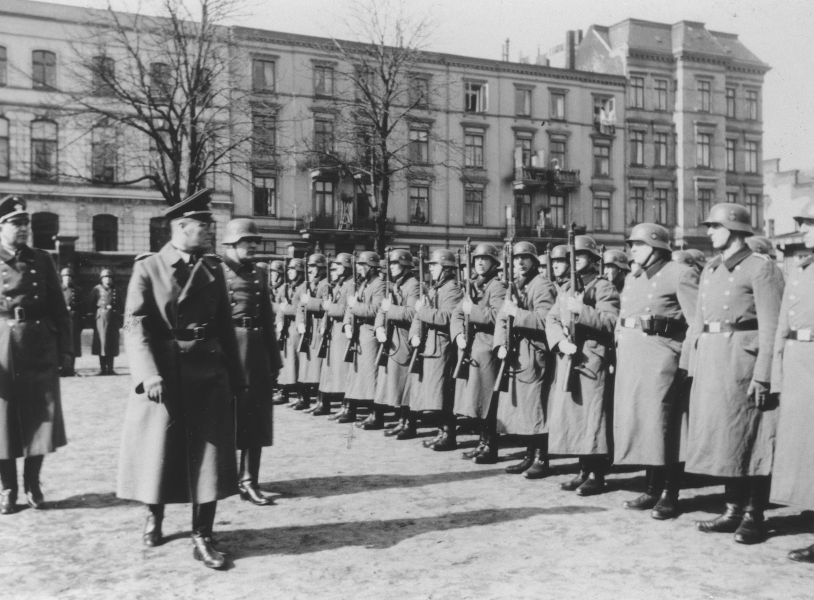 Inspection of members of Police Battalion 101 by their order police officers in a public square in Lodz. 

One image from a photograph album belonging to a member of Police Battalion 101.