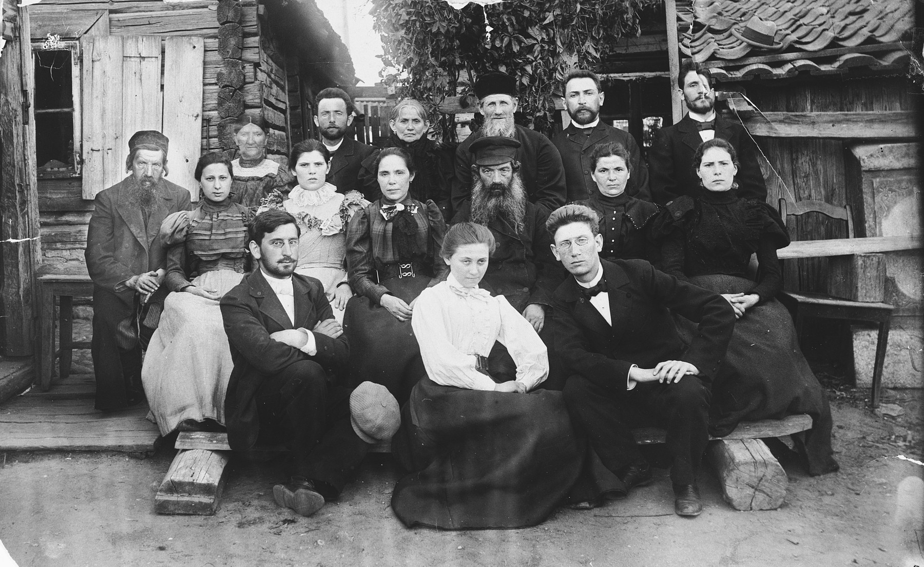 Portrait of the Magid family in front of their home in Snipishok, on the outskirts of Vilna.  

Pictured is Abram (Dov Ber) Magid (bottom row, right) with his sisters Tzivia, Rivka, Rachel and Esther, and other relatives.