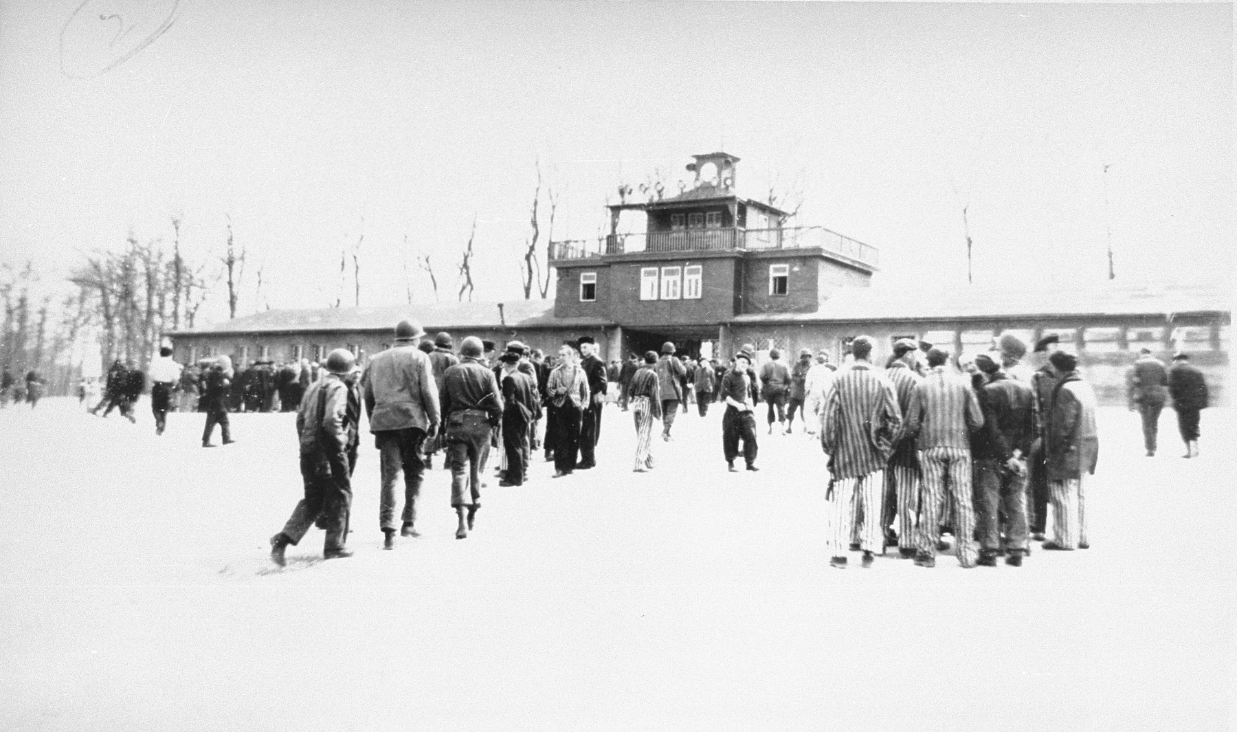 American soldiers and liberated prisoners on the Appellplatz (central plaza) of Buchenwald, behind the entrance of the camp.