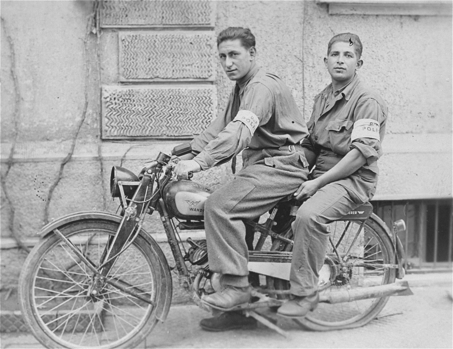 Two members of the Jewish police in the Landsberg displaced persons camp ride on a motorcycle.

Pictured in front is Emil Herskowicz.