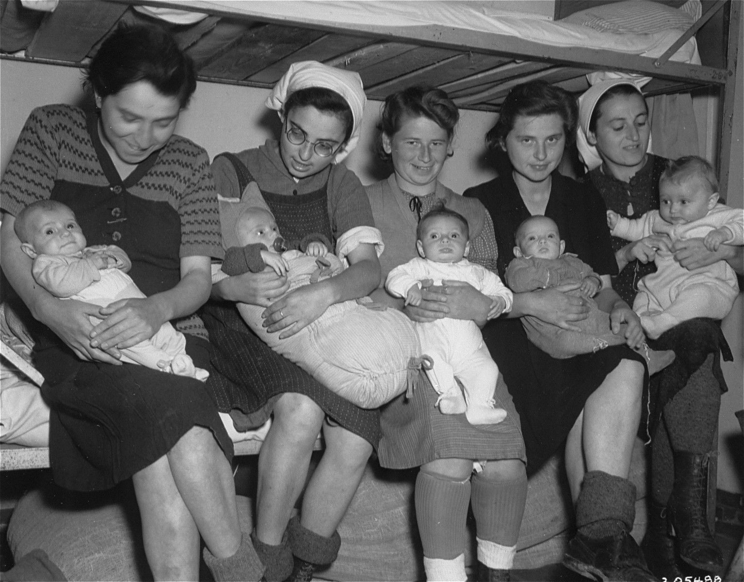 Group portrait of five Hungarian Jewish mothers and their infants in a Dachau sub-camp in Germany.

Pictured from left to right are:  Ibolya Kovacs with her daughter Agnes; Suri Hirsch with her son Yossi; Eva Schwartz with her daughter Maria; Magda Fenyvesi with her daughter Judit; and Boeszi Legmann with her son Gyuri.  Not pictured are: Dora Loewy and her daughter Szuszi; and Miriam Schwarcz Rosenthal and her son Laci (Leslie).