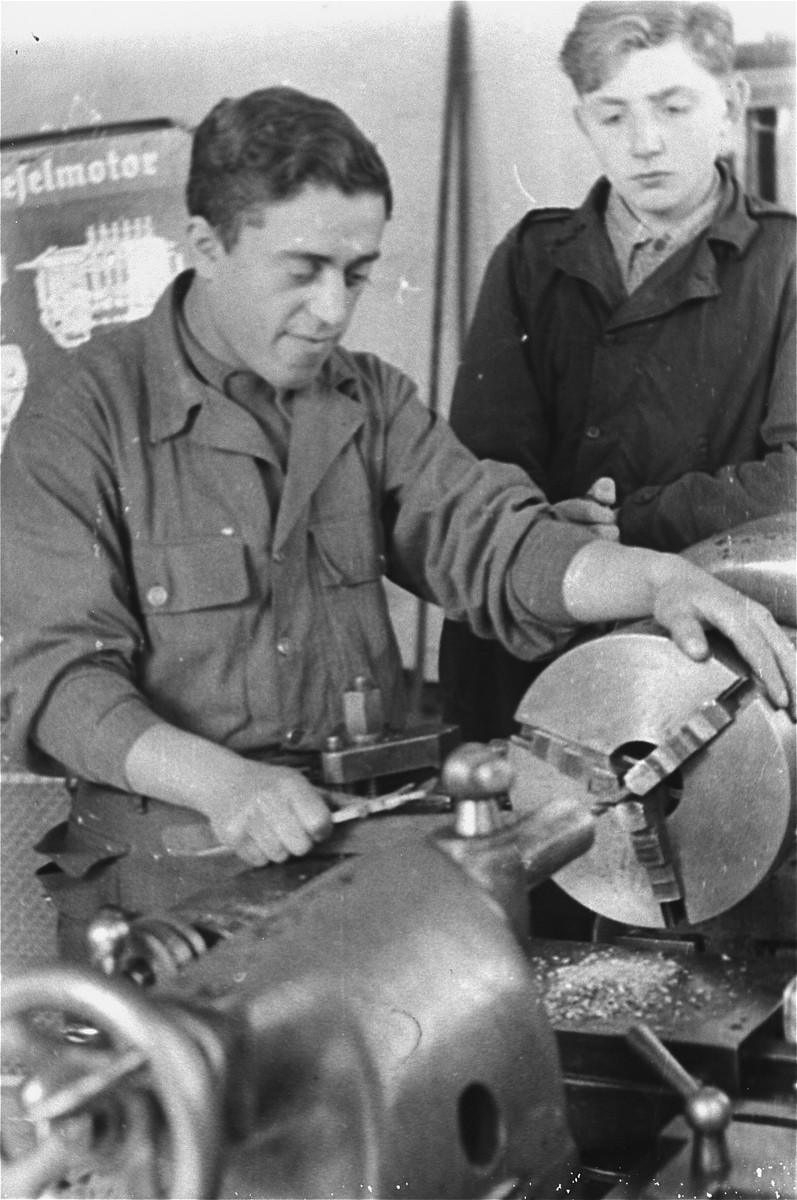 Two men work with a piece of machinery in an ORT (Organization for Rehabilitation through Training) metal workshop training program in the Landsberg displaced persons' camp. [Oversized print]