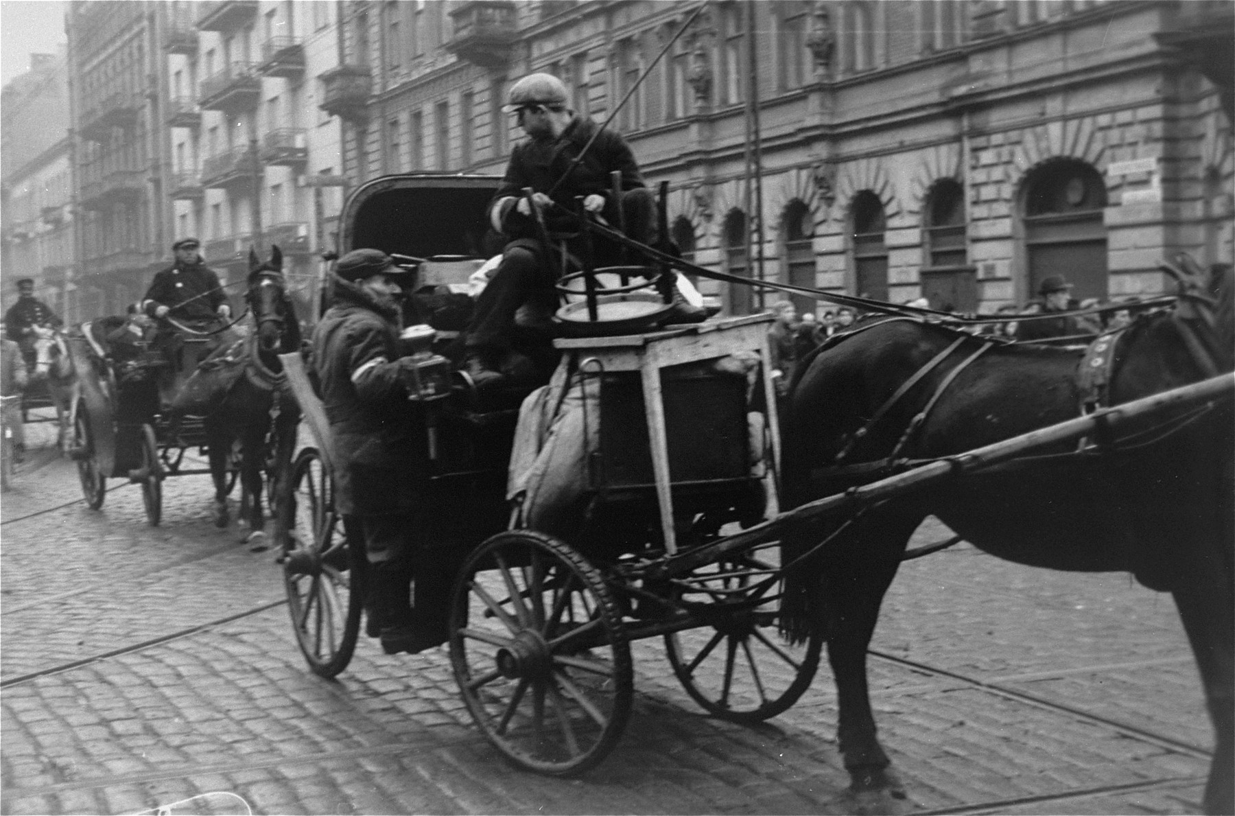 A driver leads a horse-drawn carriage along a street in the Warsaw ghetto.