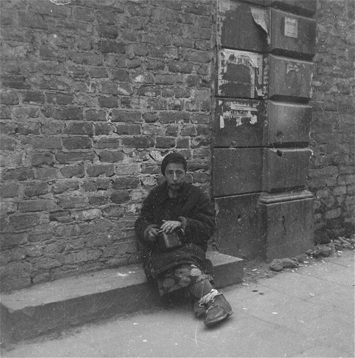 A destitute woman on the street in the Warsaw ghetto.

Joest's caption reads: "I believe that this woman was a black-marketeer offering something or other for sale.  She fearfully hid the pot in front of me and was thoroughly afraid around the police."