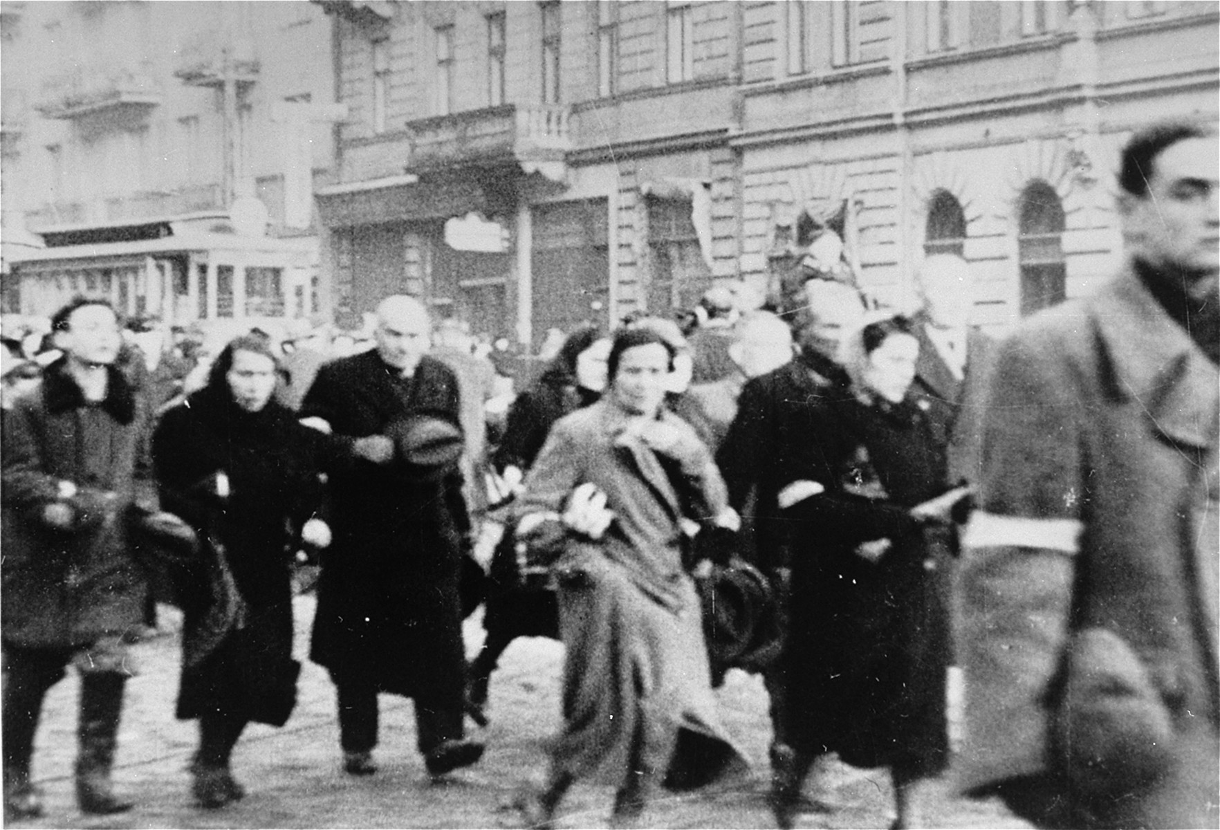 Jews who have been rounded-up for deportation in the Warsaw ghetto walk along a street to the assembly area.