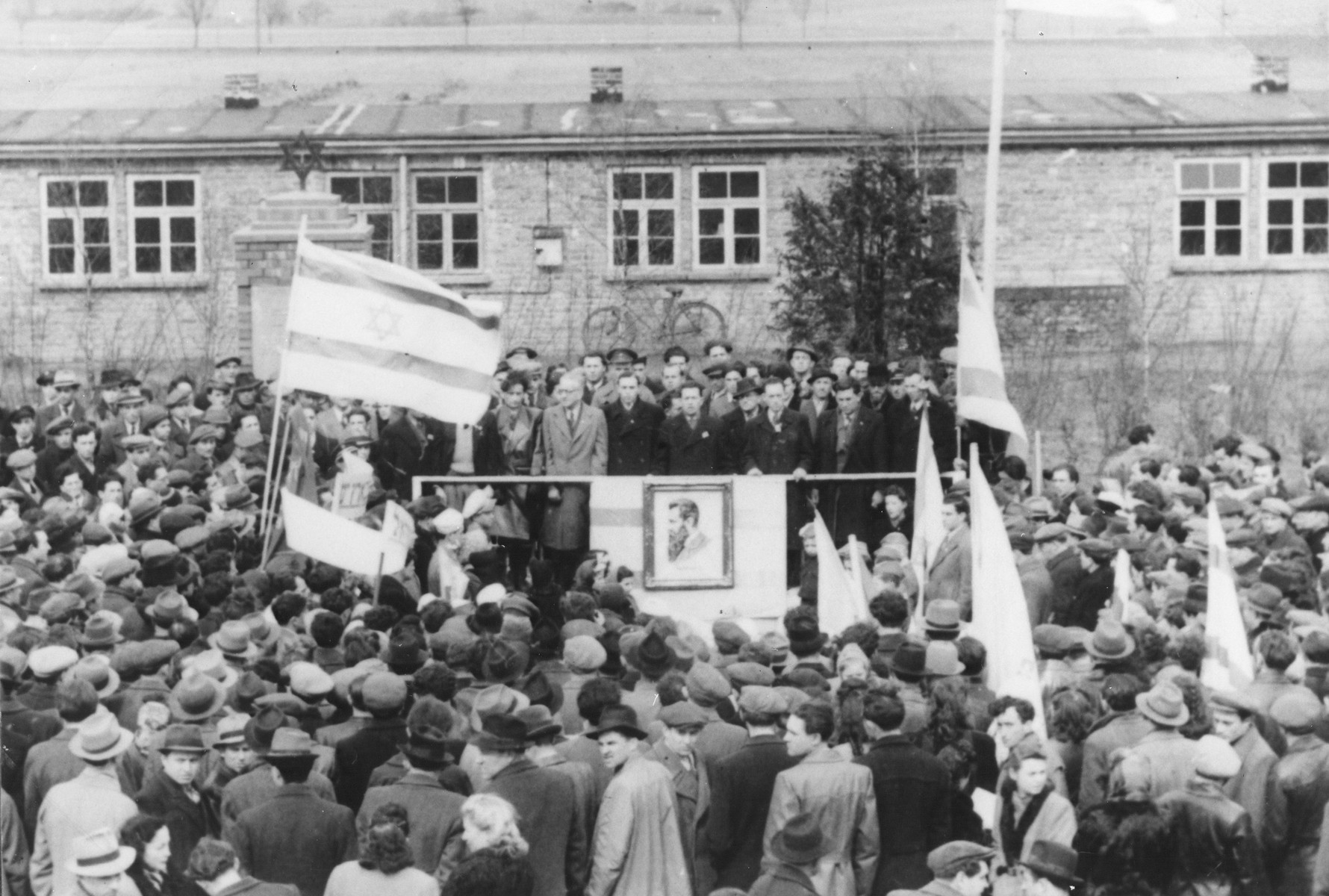 A large crowd rallies in a Zionist demonstration in the Zeilsheim displaced persons' camp.

Pictured among the men on the platform is Jona Wisgardsky.
