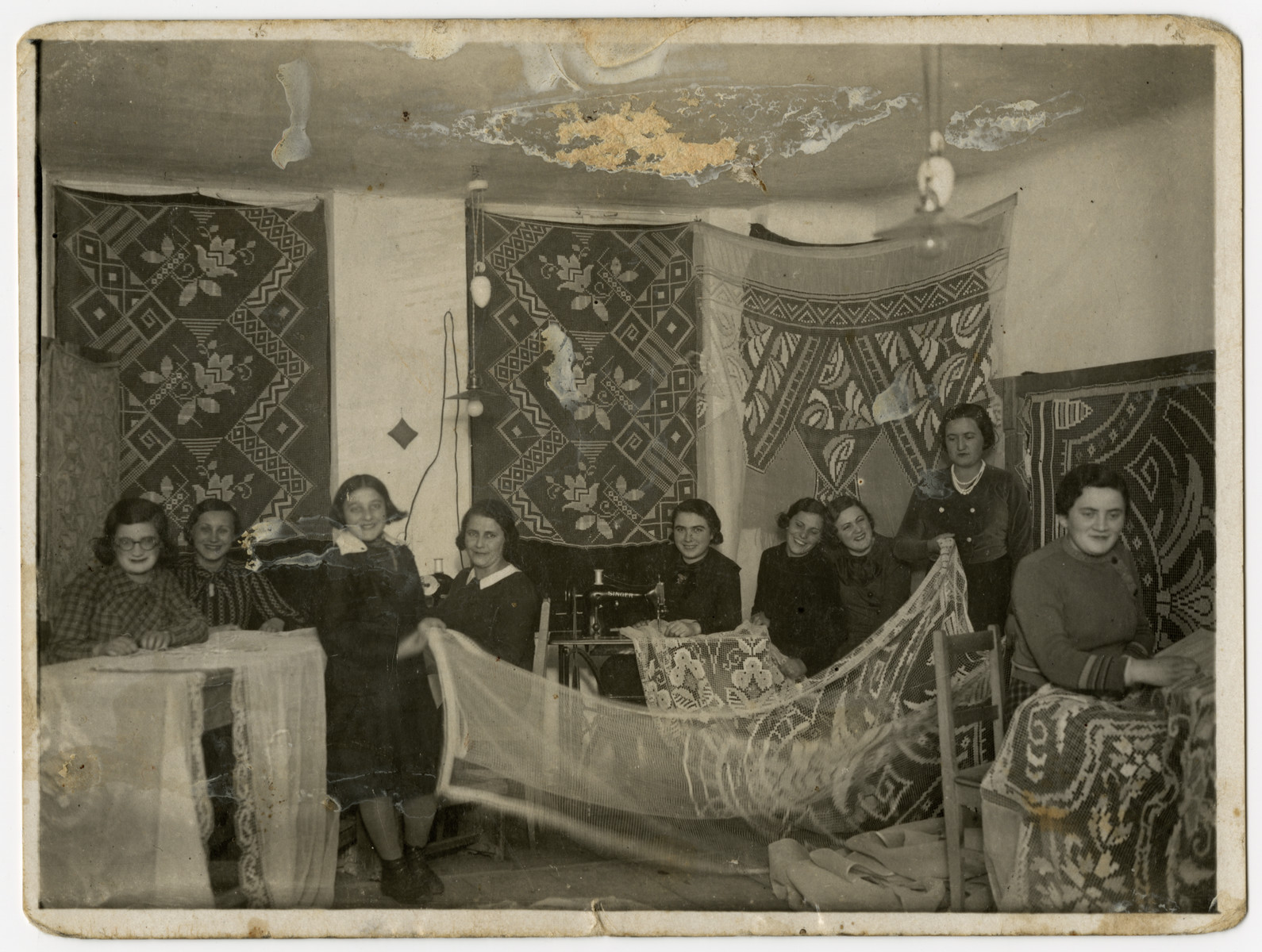 A group of Beit Yaakov women sew lace curtains in Rymanow, Poland.  Pictured at the right is the donor's mother, Sara Ginsburg Keller.