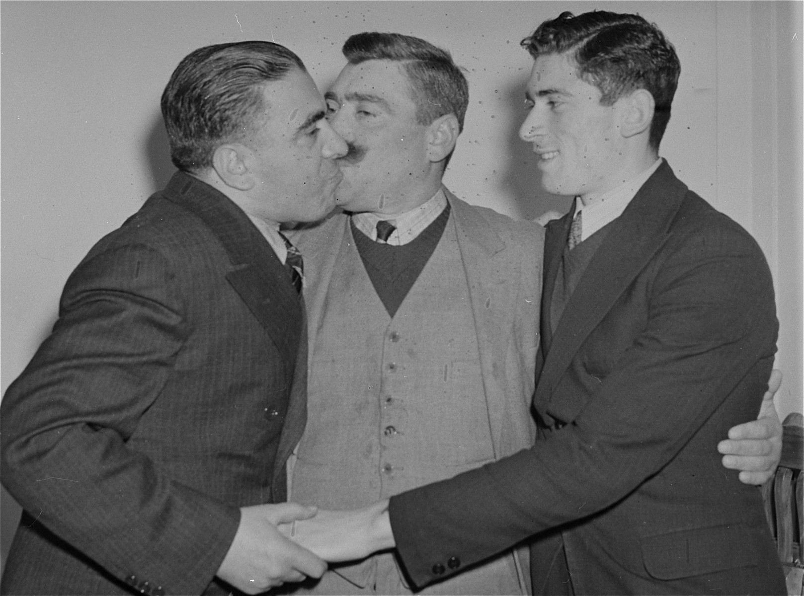 Polish-Jewish immigrant Tewja Soshnick (center) greets his brother Isidore (left) upon his arrival from Poland aboard the SS Queen Mary.  

At the right is Tewja's son, Yachem.  Tewja, who lost his business in Poland, will receive a half interest in his brother's new restaurant as a guarantee that he will not become a public charge.  His wife and seven other children are expected to arrive in several months.