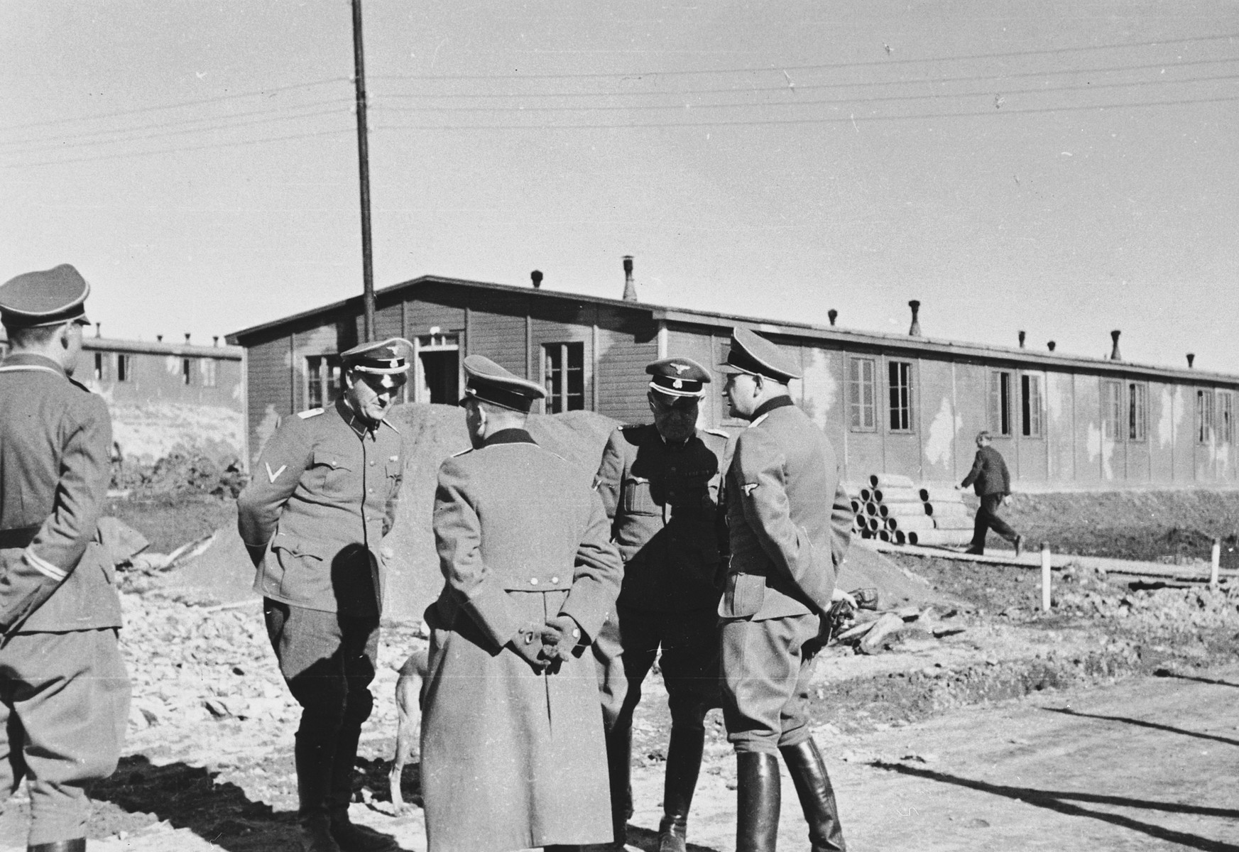 A group of SS officers converse outside at a construction site in the Hinzert concentration camp.