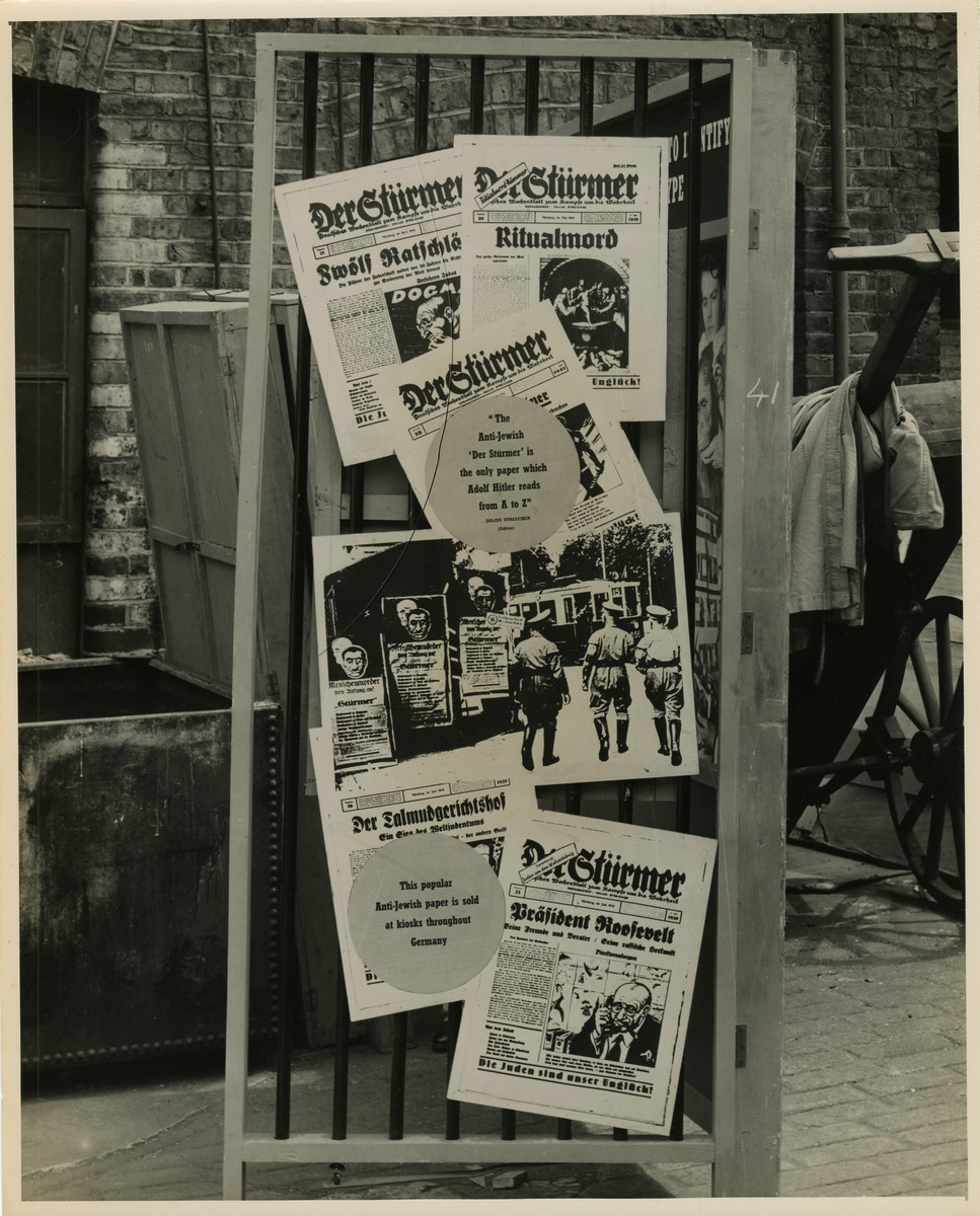 Panel from a 1944 exhibition in London, England, entitled "Germany- the Evidence" showing antisemitic German Newspapers. 

Panel displays numerous antisemitic German newspapers including "Der Stuermer" and "Der Talmudgerichtshof" donning titles such as "Ritualmord" (ritual murder) and "Praesident Roosevelt" (President Roosevelt."

The back of the photo reads "British Official Photograph; Distrbuted by the Ministry of Information. D. ; The Evil We Fight.; Ministry of Information Exhibition priduced by Display & Exhibitions Division for show all over Great Britain.; Display panel"