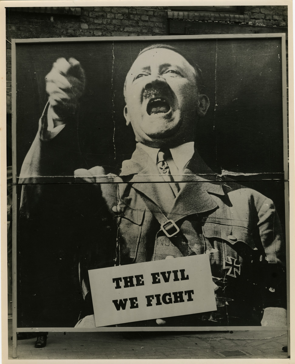 Panel from a 1944 exhibition in London, England, entitled "Germany- the Evidence" showing Adolf Hitler. 

The exhibit panel reads "The Evil We Fight."

The back of the photo reads "British Official Photograph; Distrbuted by the Ministry of Information. D. ; The Evil We Fight.; Ministry of Information Exhibition priduced by Display & Exhibitions Division for show all over Great Britain.; Display panel"