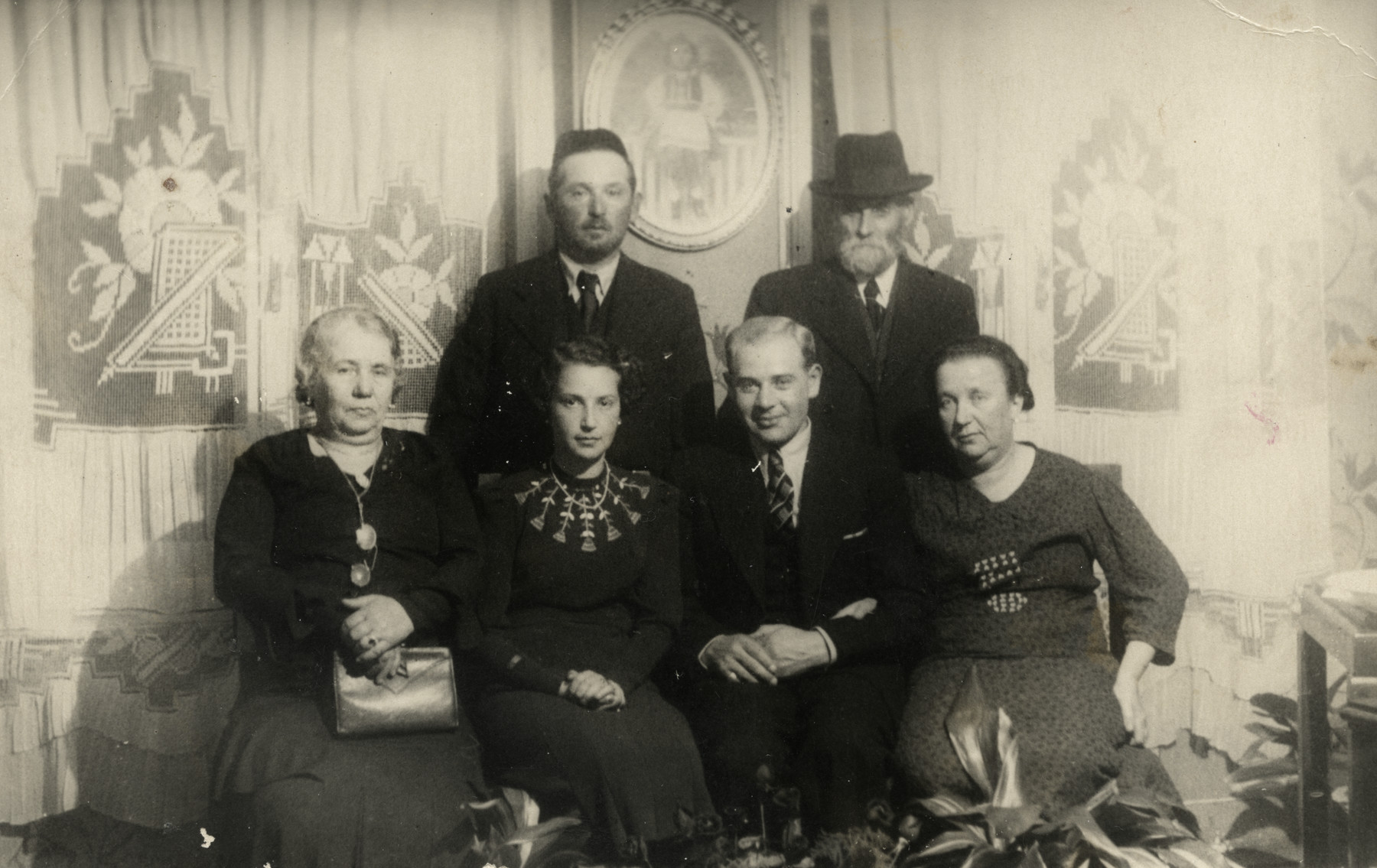 A group of six people poses in a living-room in prewar Krakow.

Among those pictured are Roman Berger and his wife (great-grandparents of the donor).