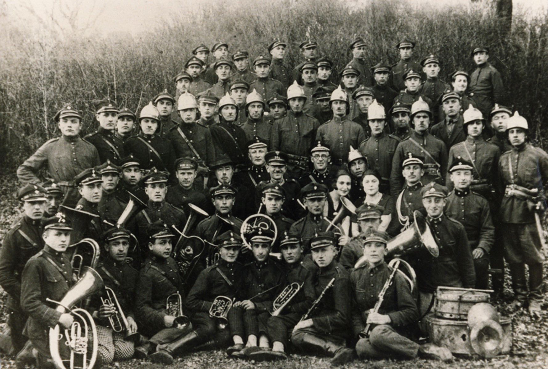 Group portrait of members of the Nowogrodek fire brigade, many are holding musical instruments.