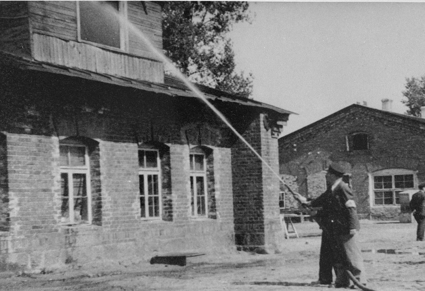 Members of the Kovno ghetto firefighting brigade aim a hose at an upstairs window of a house in the ghetto.