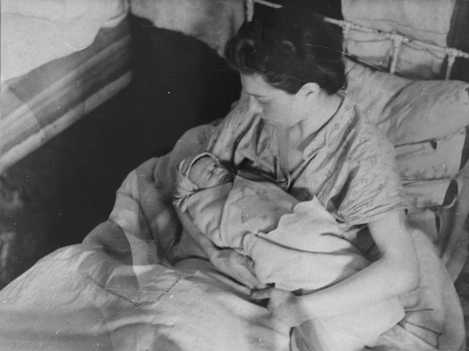 A mother cradles her new born baby in the Kovno ghetto hospital.

The child is swaddled in a blanket with a Star of David.
