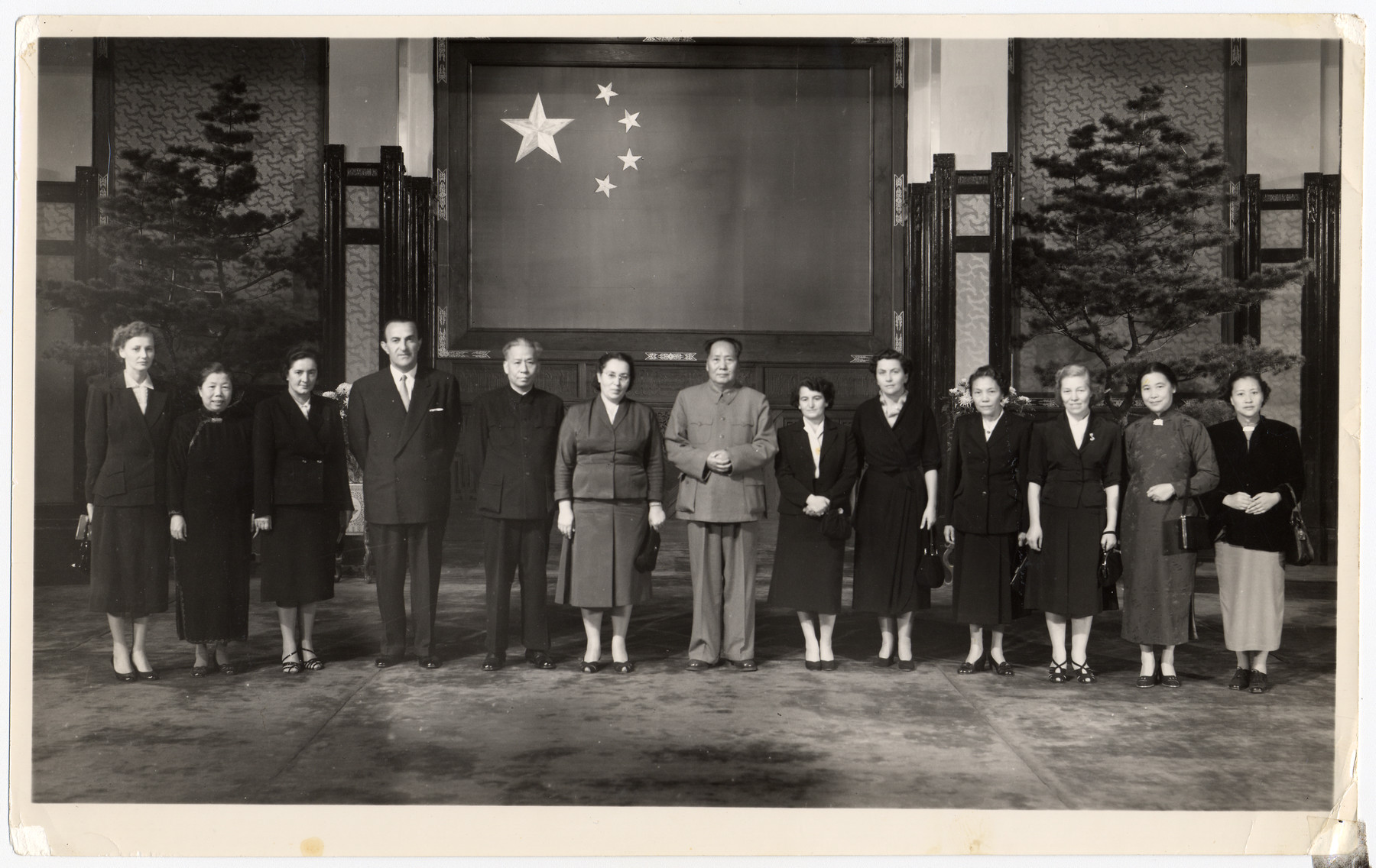 Members of the Yugoslav delegation to China pose with Mao Zedong, in front of the flag of the People's Republic of China.

Among those pictured are Mao Zedong (center) and Jamila Kolonomos (to his left).