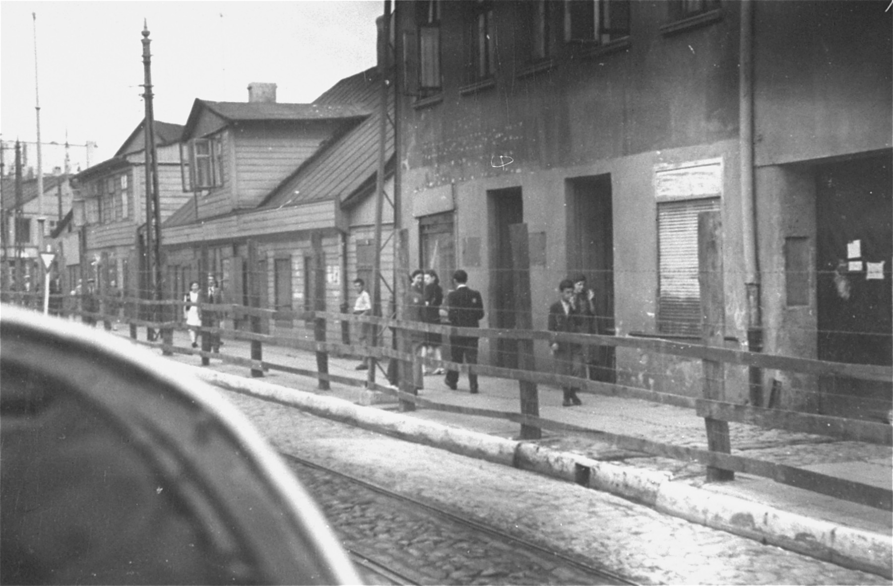 Lodz ghetto Jews behind the wooden and barbed wire fence that separated the Lodz ghetto from the rest of the city (probably taken from Zgierska Street).