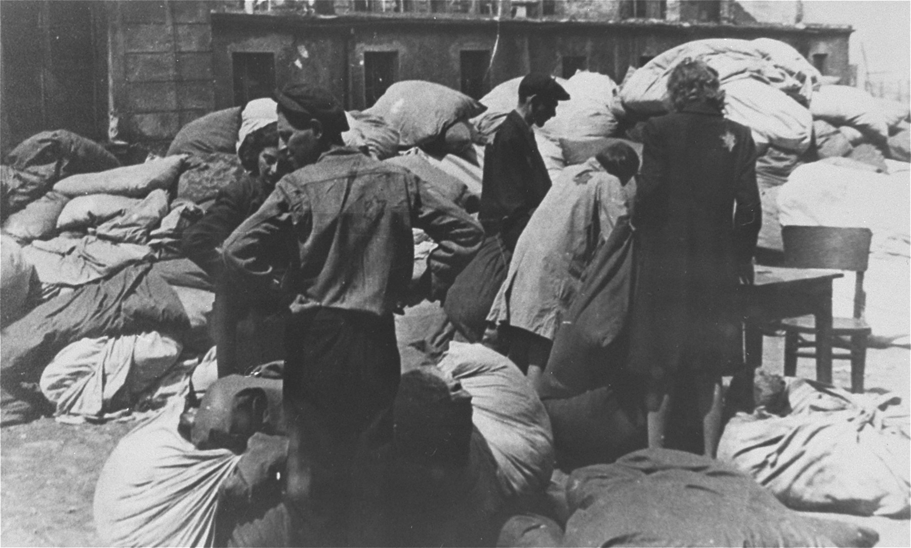 Jewish men and women prepare to sort  clothing that was confiscated from the deportees to the Chelmno death camp.