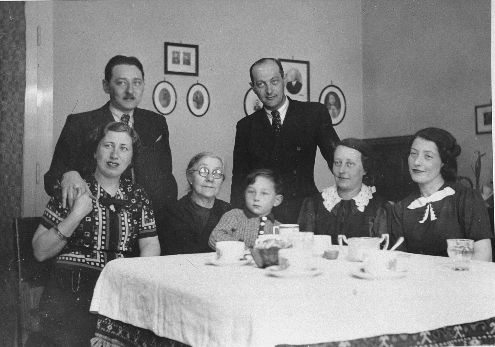 Members of the extended Kornhauser family sit around a dining room table.  

Pictured from left to right are: Mr. and Mrs. Laszlo Kornhauser, Gyorgy Pick, Malvina (Spitzer) Kornhauser, Istvan and Margit Pick, and Mrs. Karoly Kornhauser.
